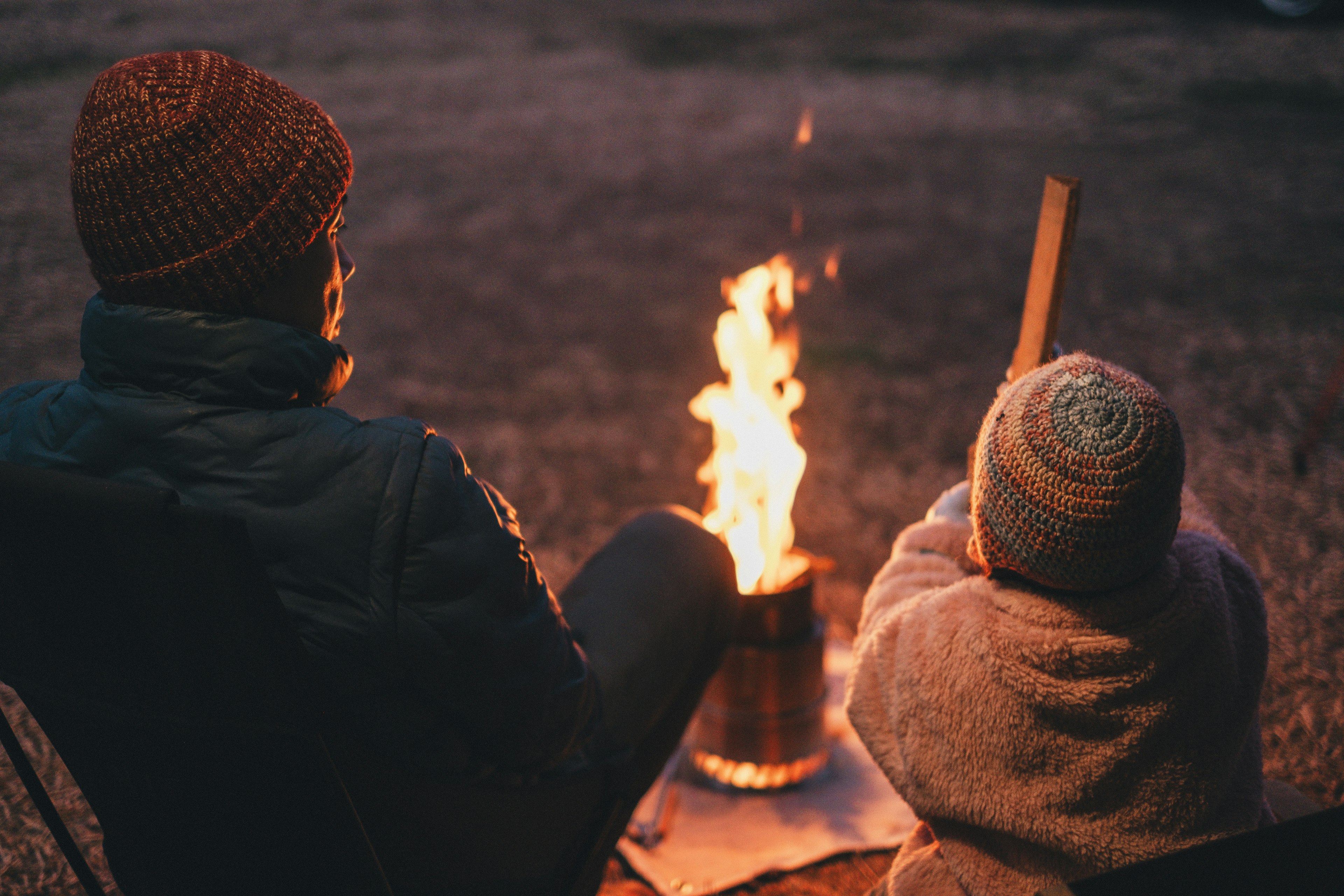 Un adulto e un bambino seduti accanto a un falò di notte