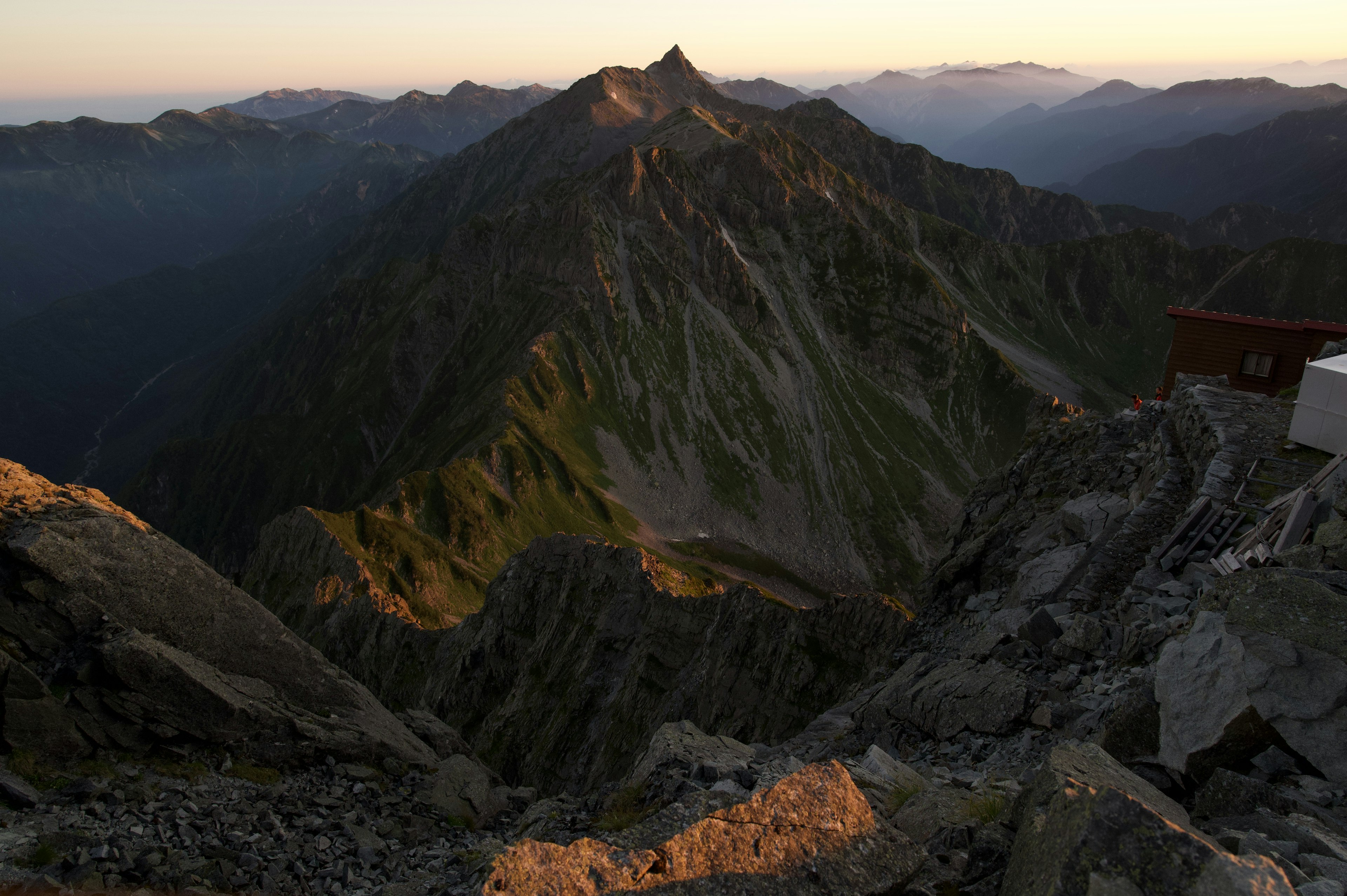 Mountain landscape illuminated by sunset featuring green slopes and rocky formations