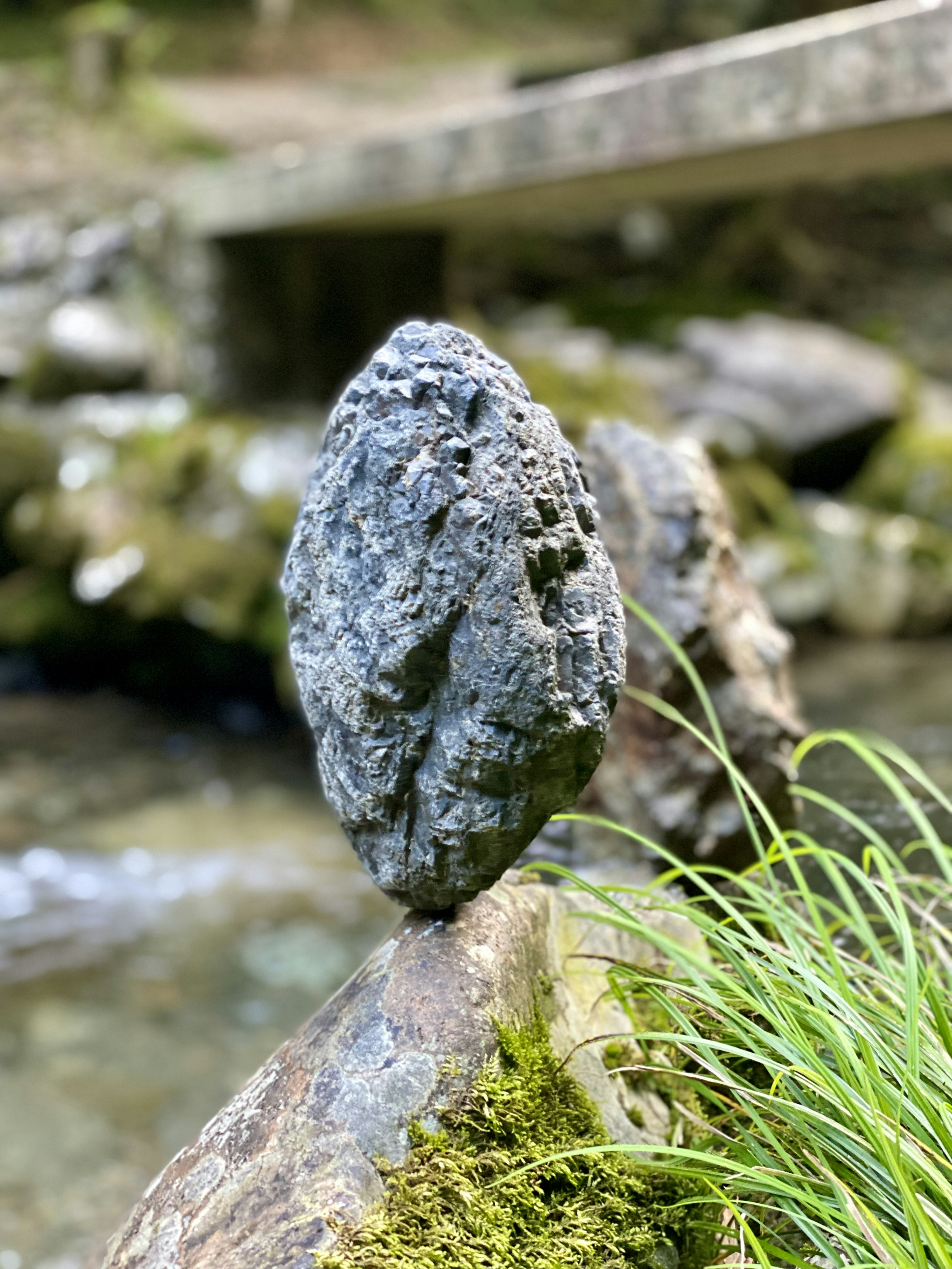 Balanced stone sculpture on a riverbank with green grass