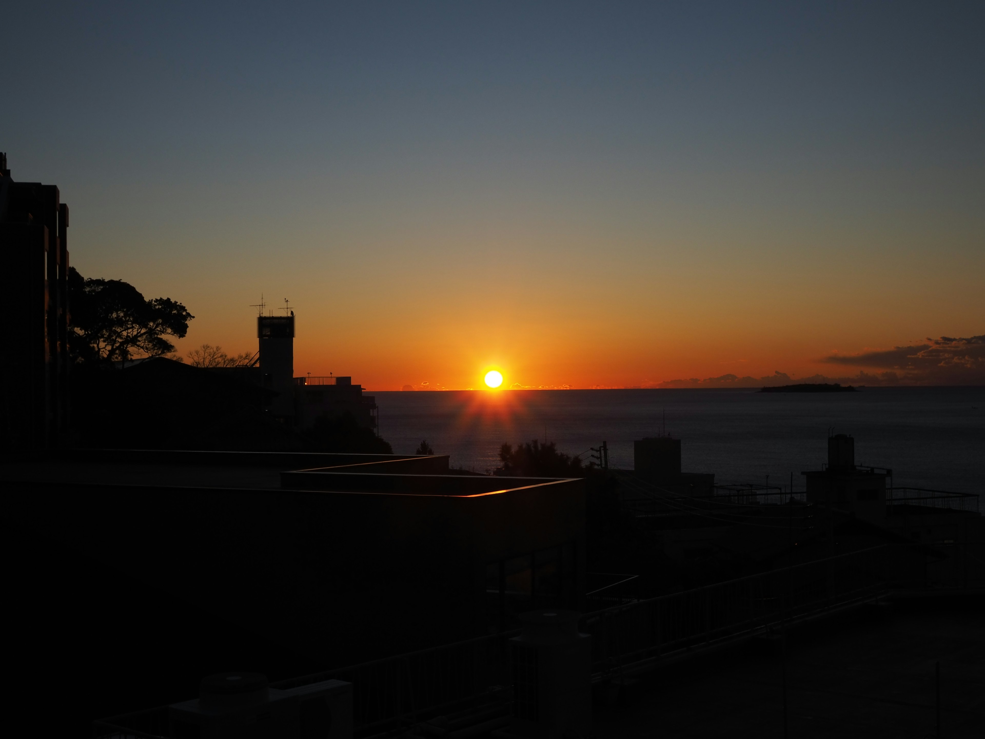 Tramonto sul mare con edifici in silhouette