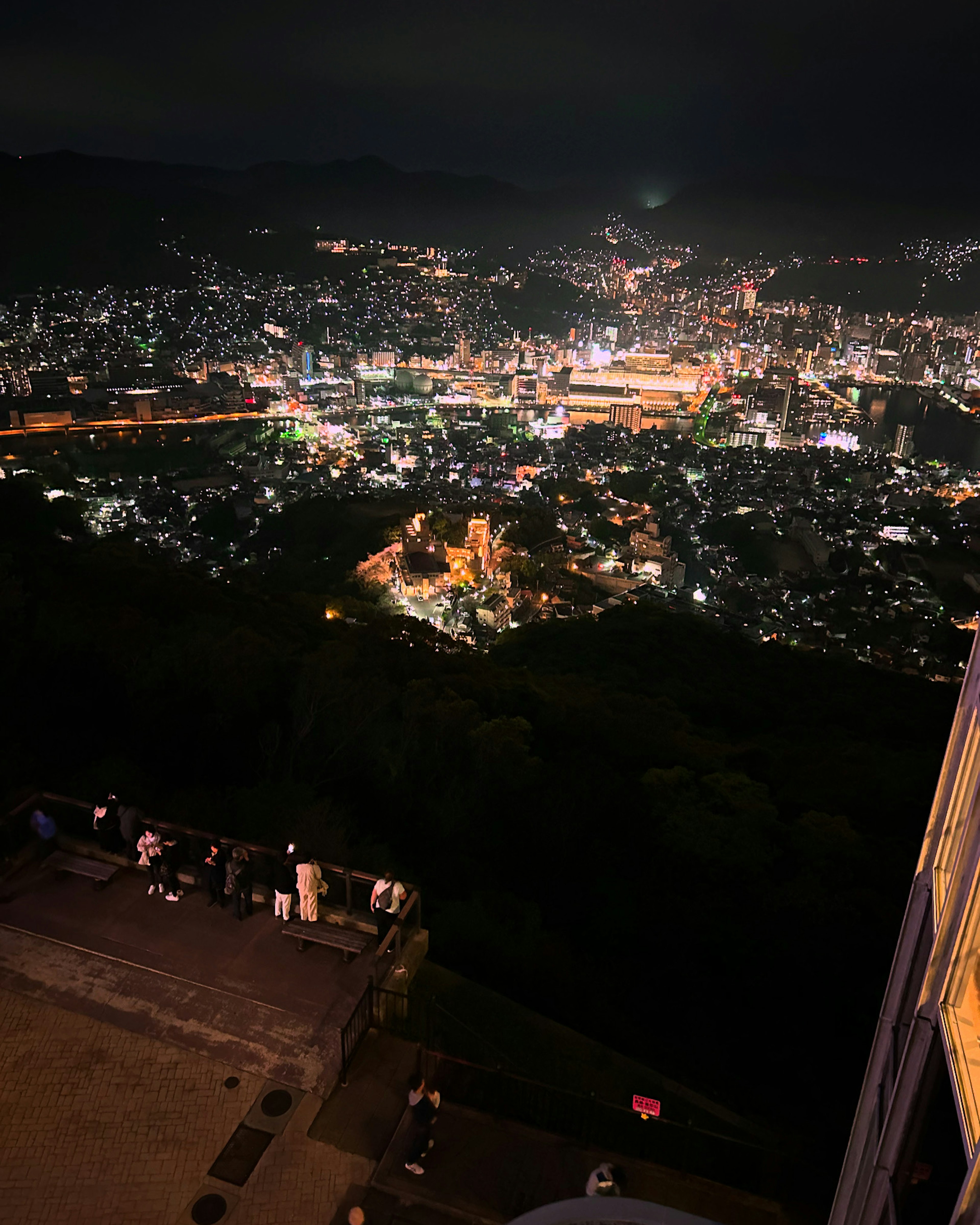 Vista notturna di una città con edifici illuminati e montagne