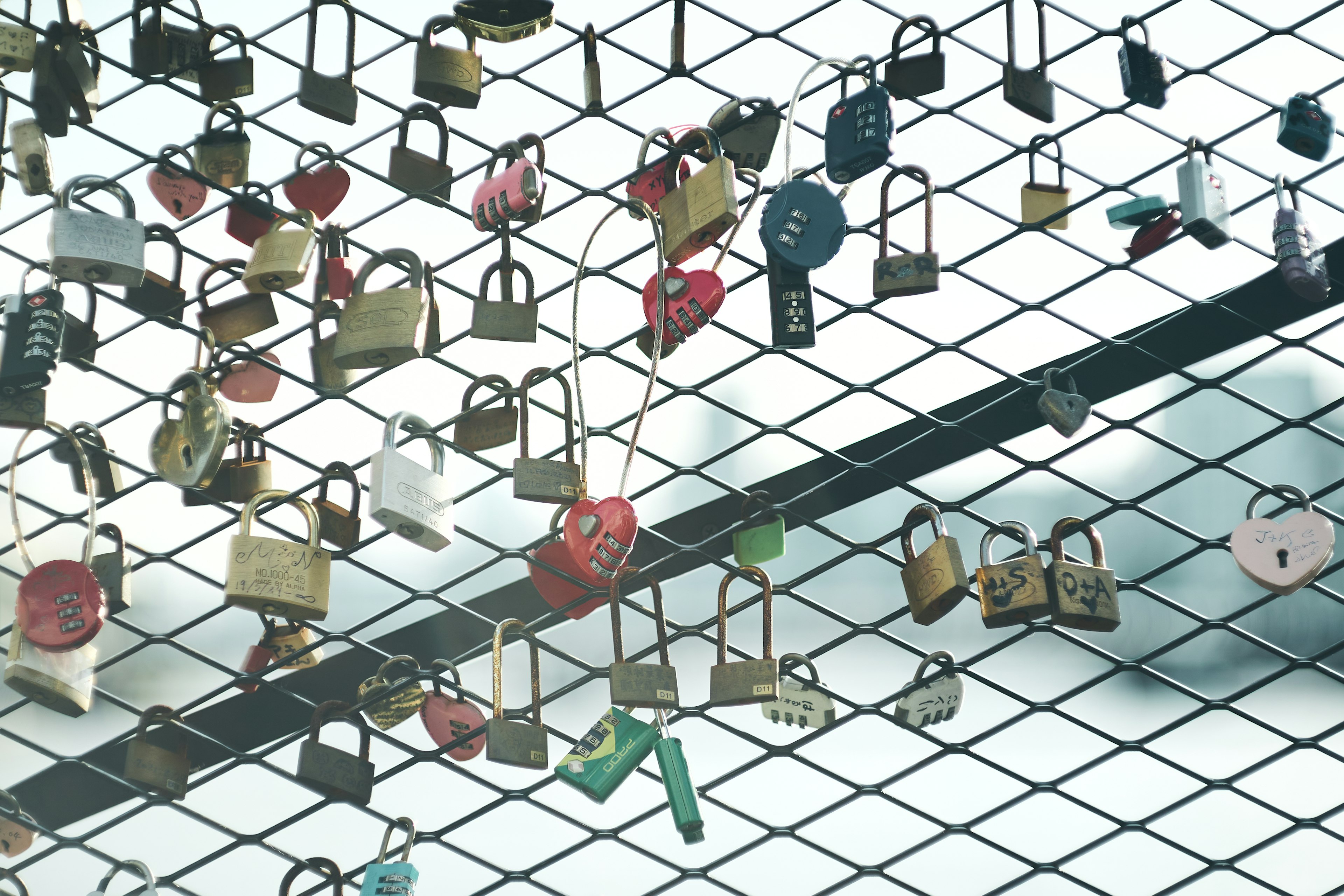 A collection of colorful padlocks hanging against a grid