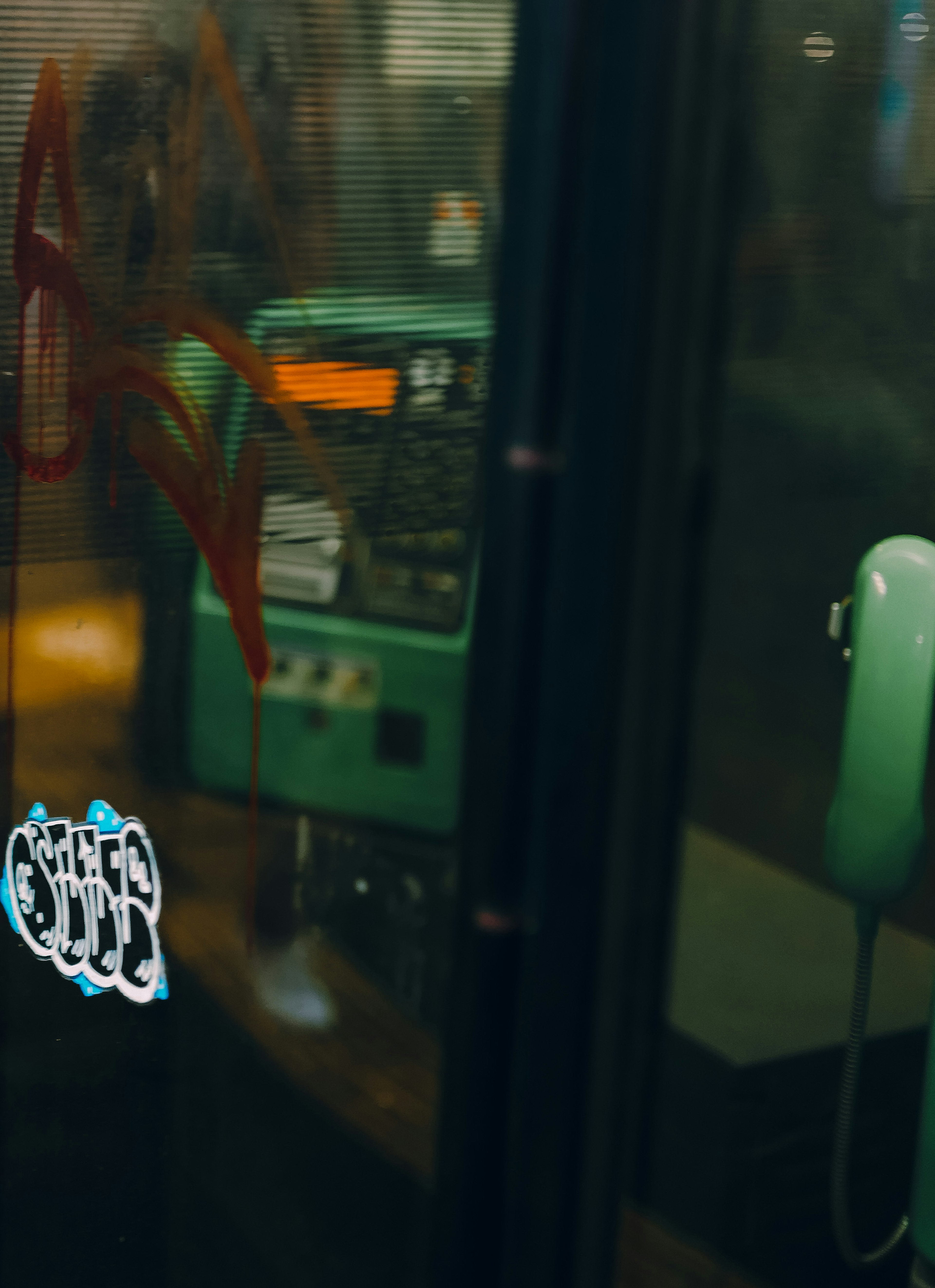 Intérieur d'une ancienne cabine téléphonique avec un téléphone vert et des graffitis sur les murs