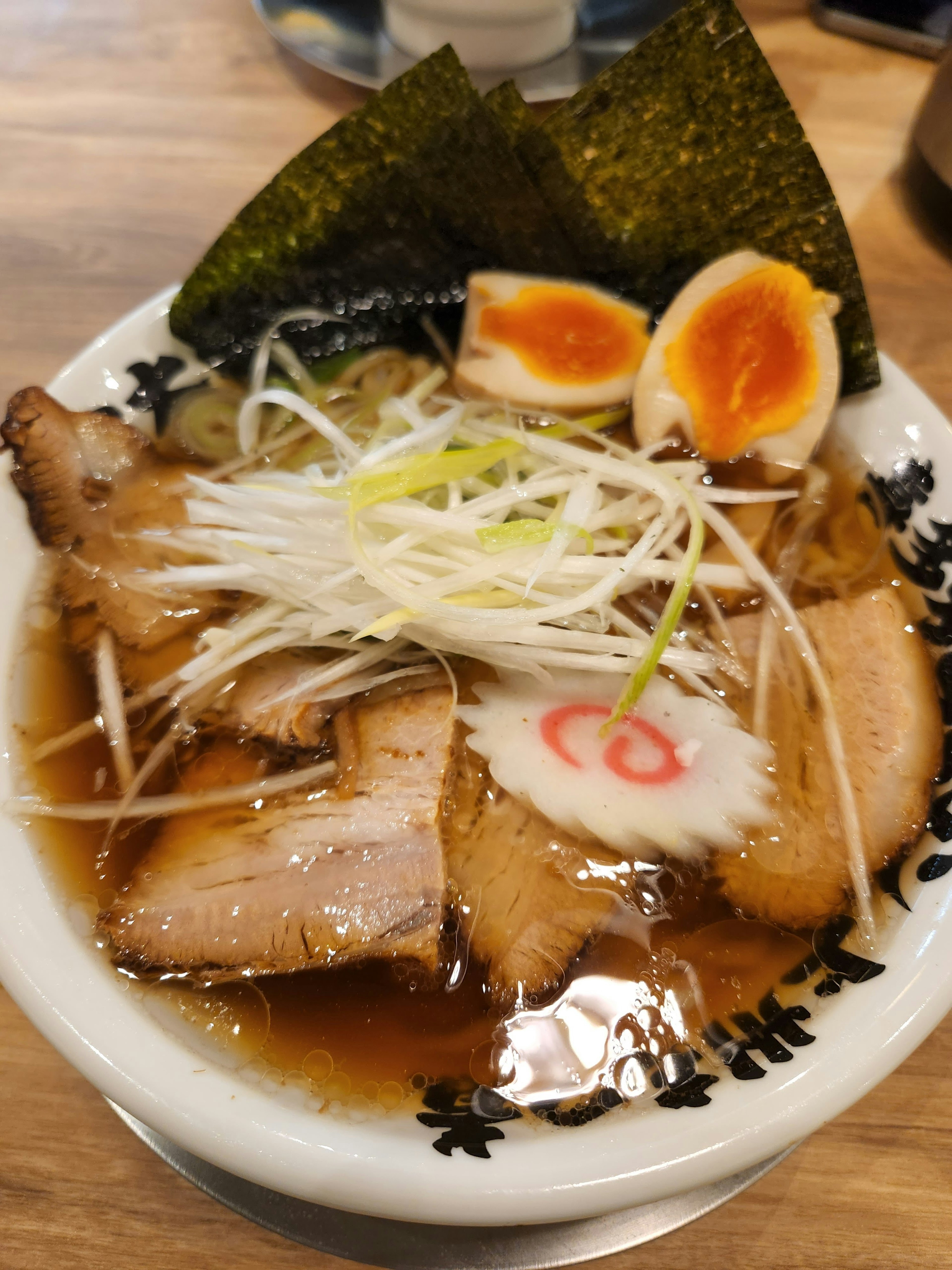 Delicious ramen bowl topped with chashu, soft-boiled eggs, green onions, and nori