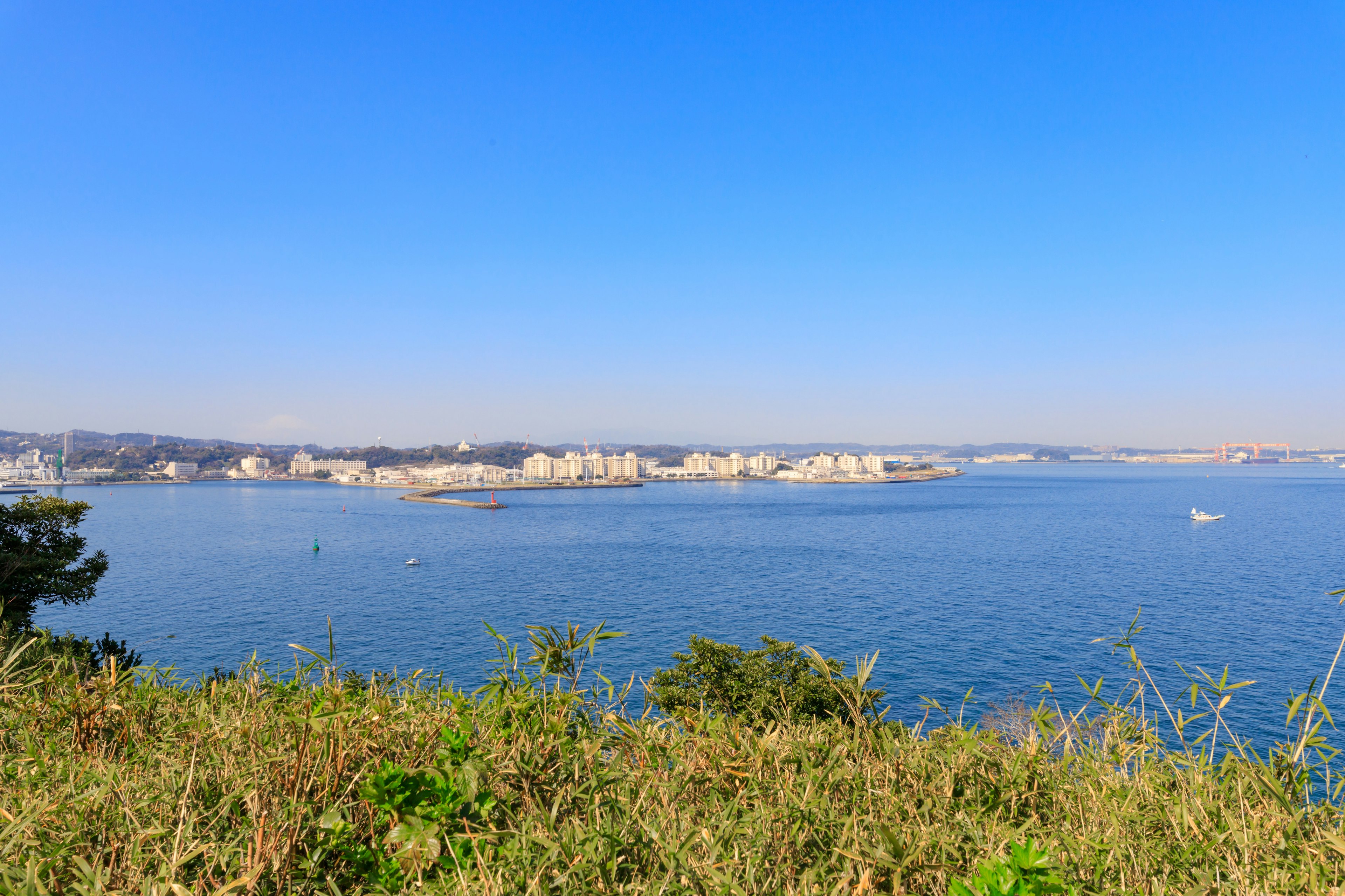 Vista escénica del cielo azul y el mar con edificios costeros y vegetación