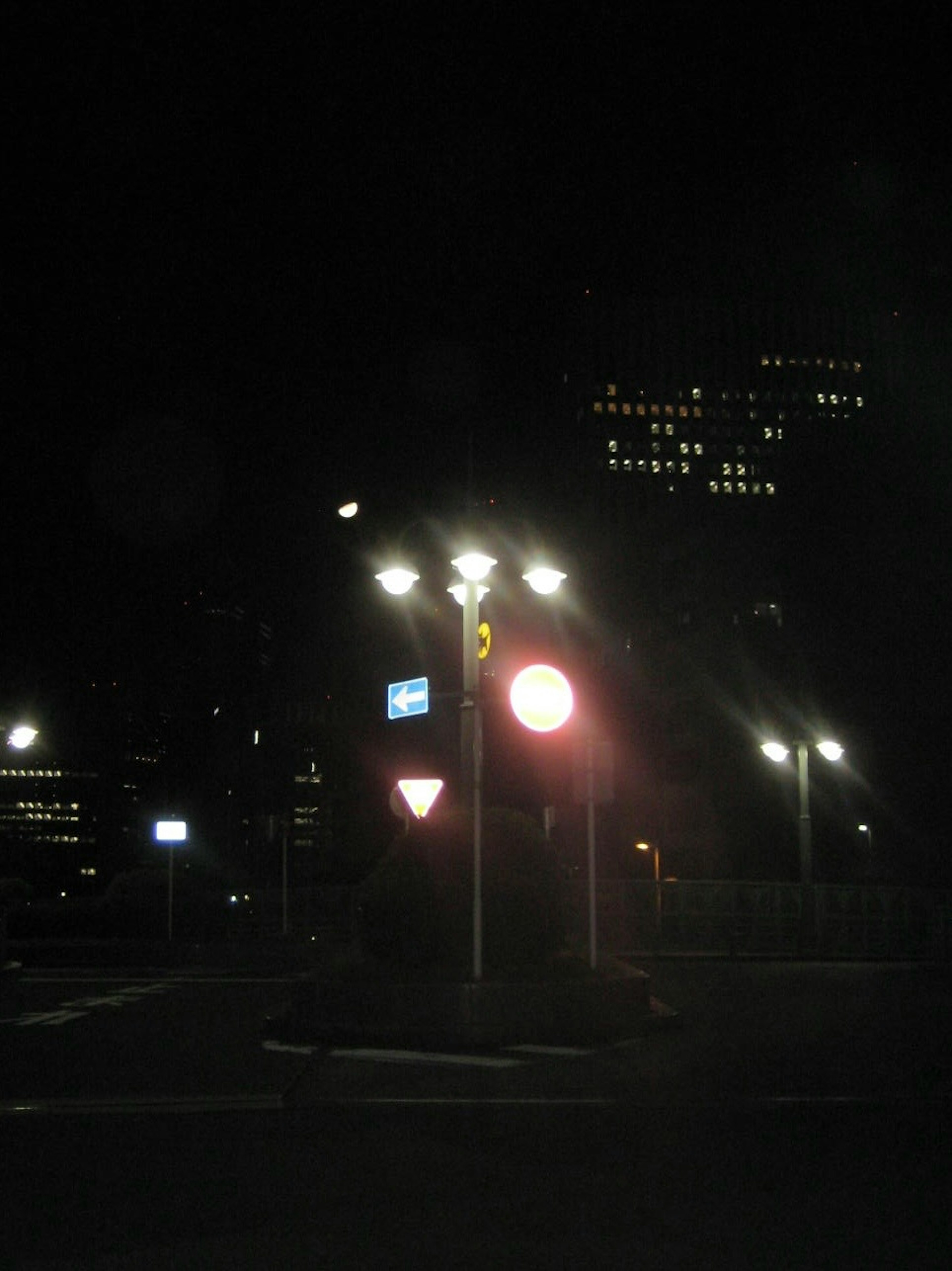 Red traffic light at a dark intersection with street lamps