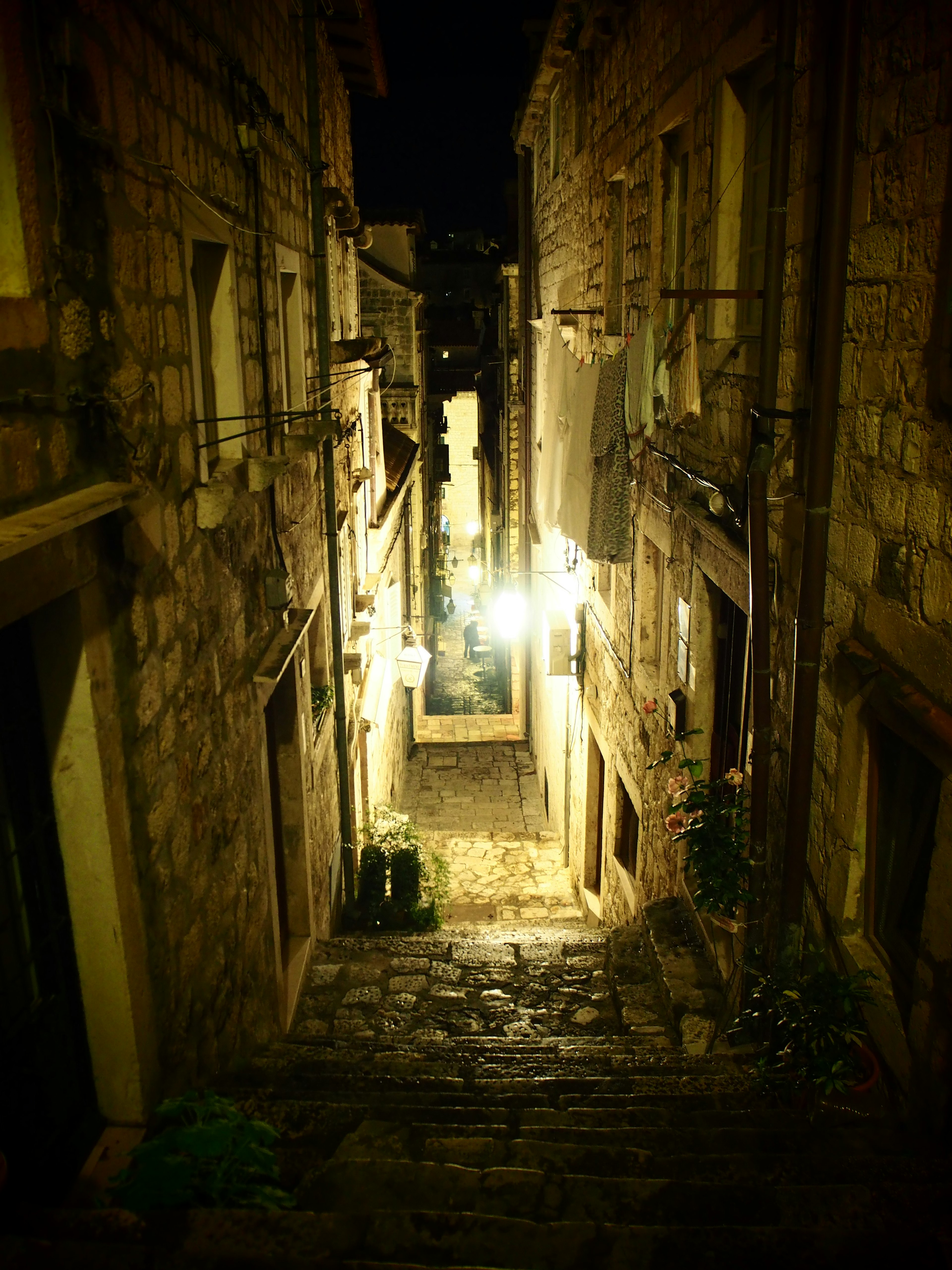 Narrow cobblestone street lined with ancient buildings and soft lighting at night