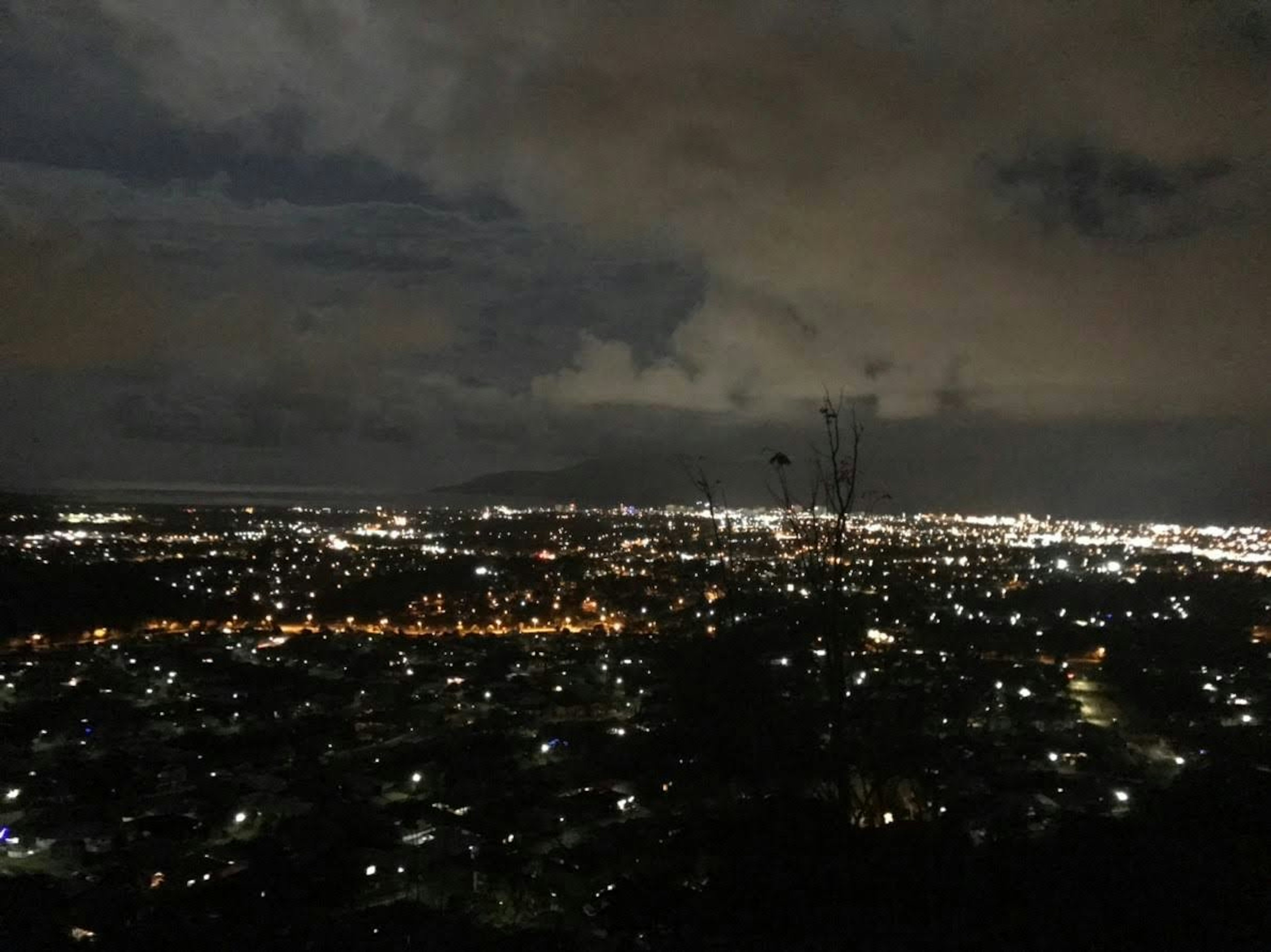 Nachtsicht auf eine Stadtlandschaft mit verstreuten Lichtern und bewölktem Himmel