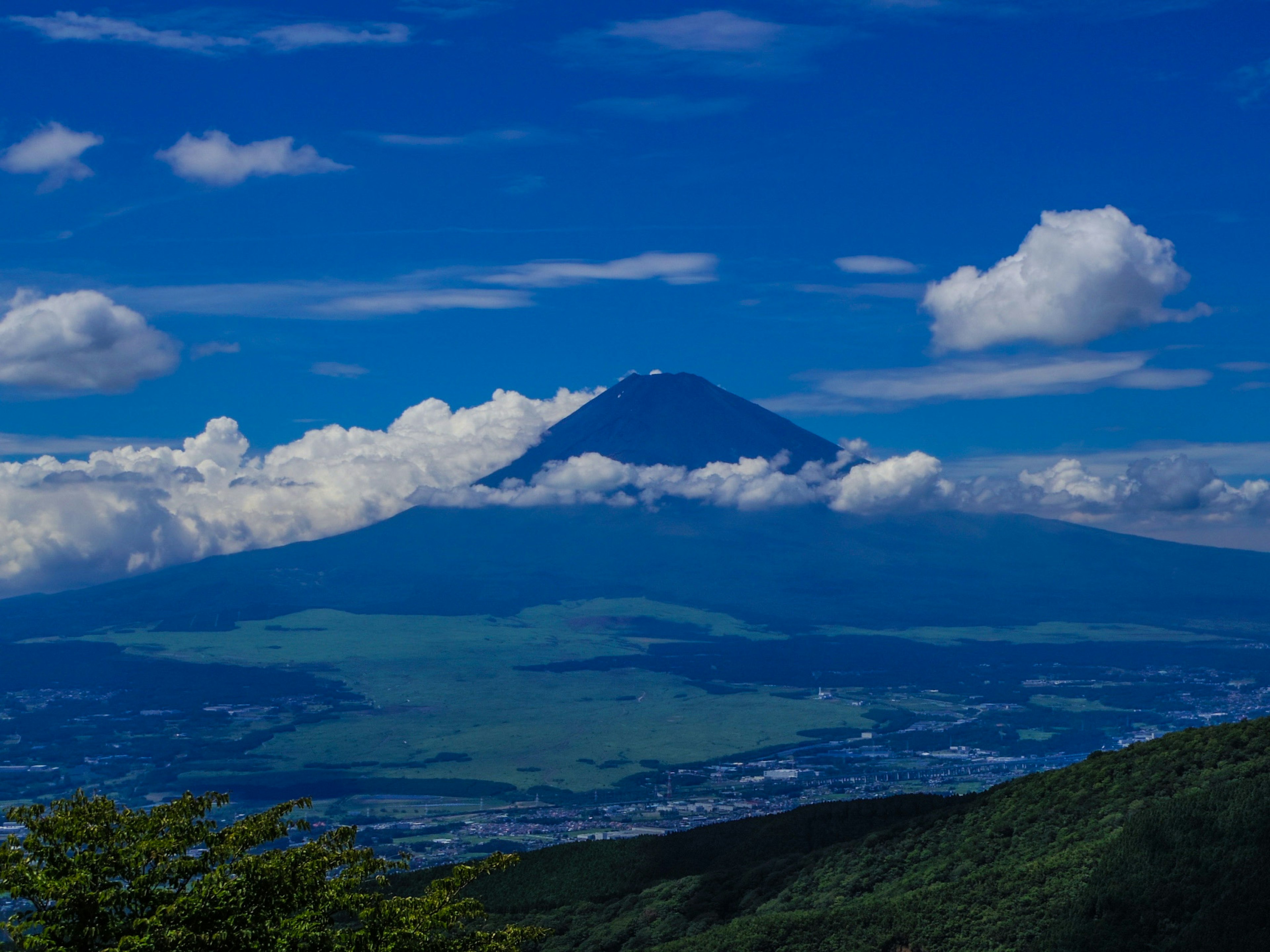 富士山在晴朗的蓝天下雄伟地耸立，四周有云