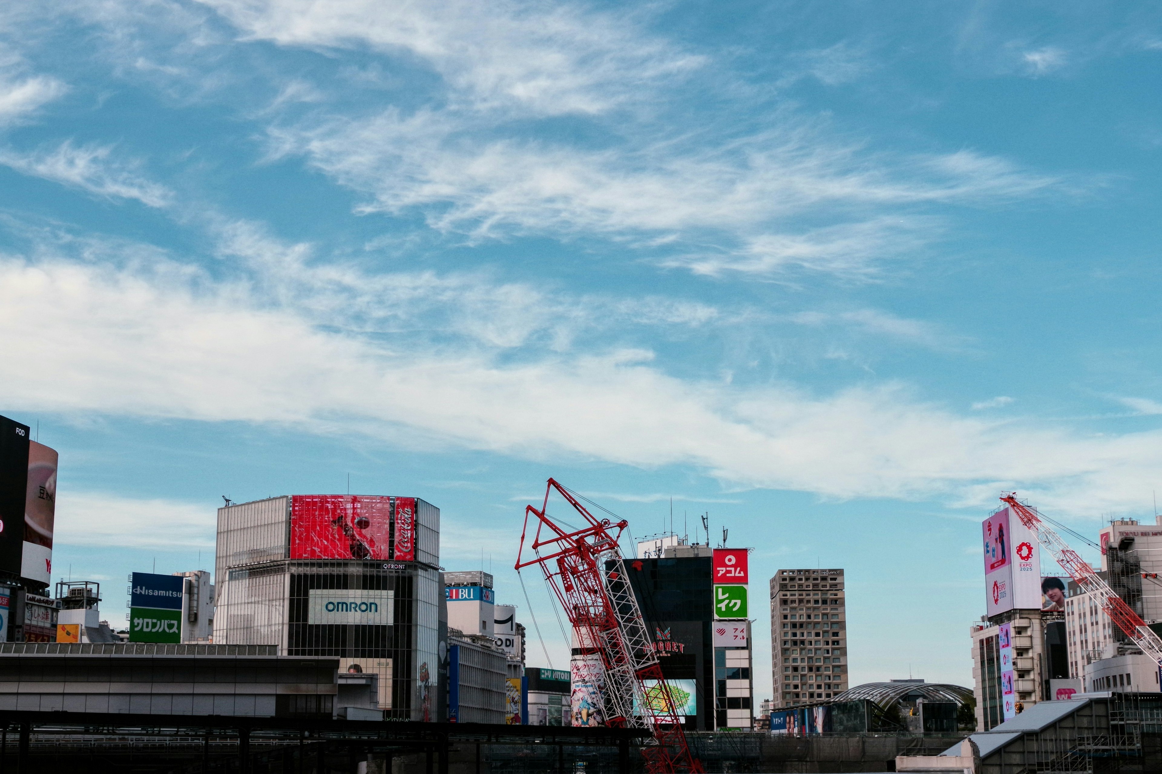 青空の下に高層ビルと広告看板が並ぶ都市風景