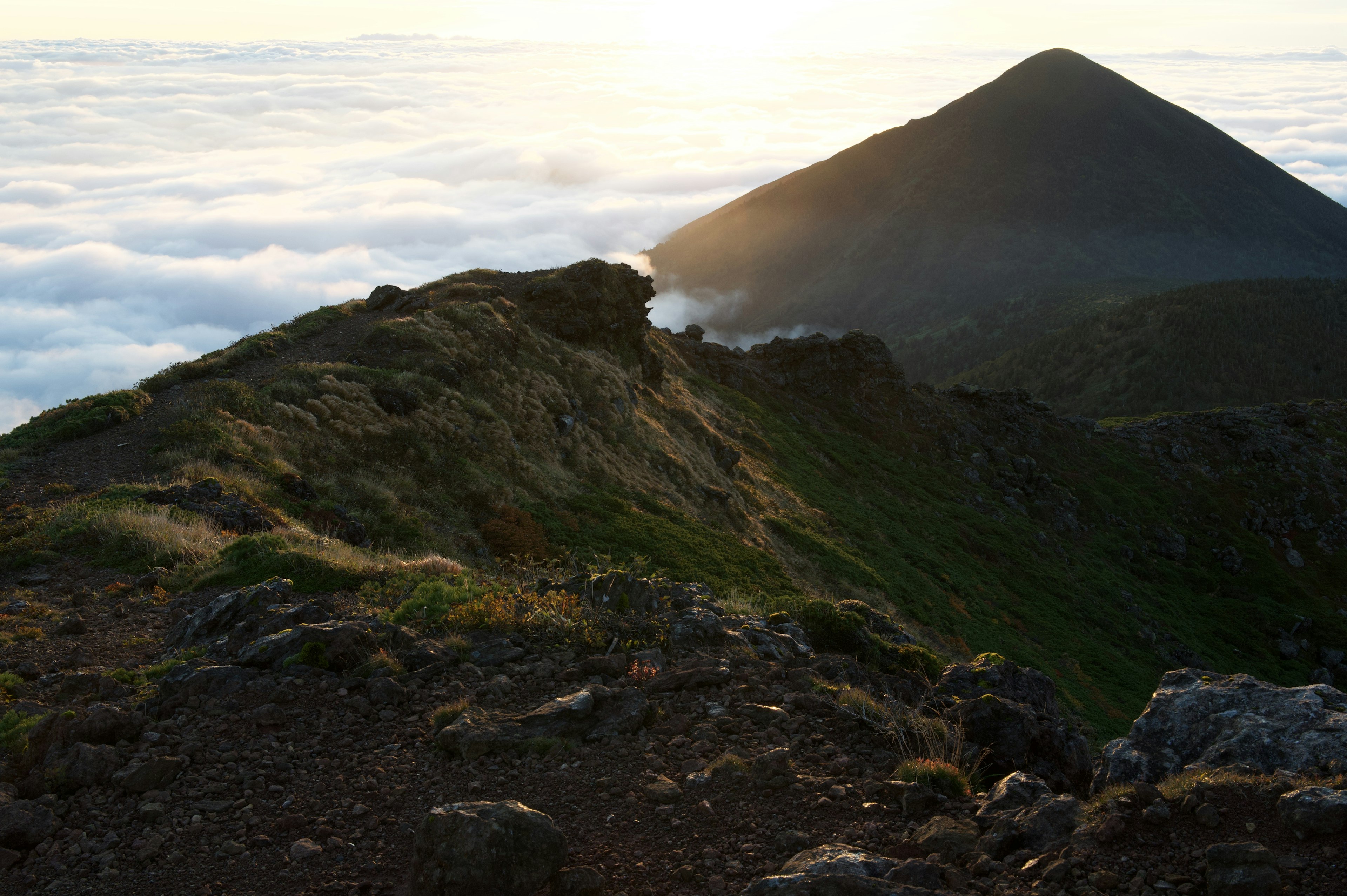 Paisaje al atardecer con cresta montañosa y mar de nubes