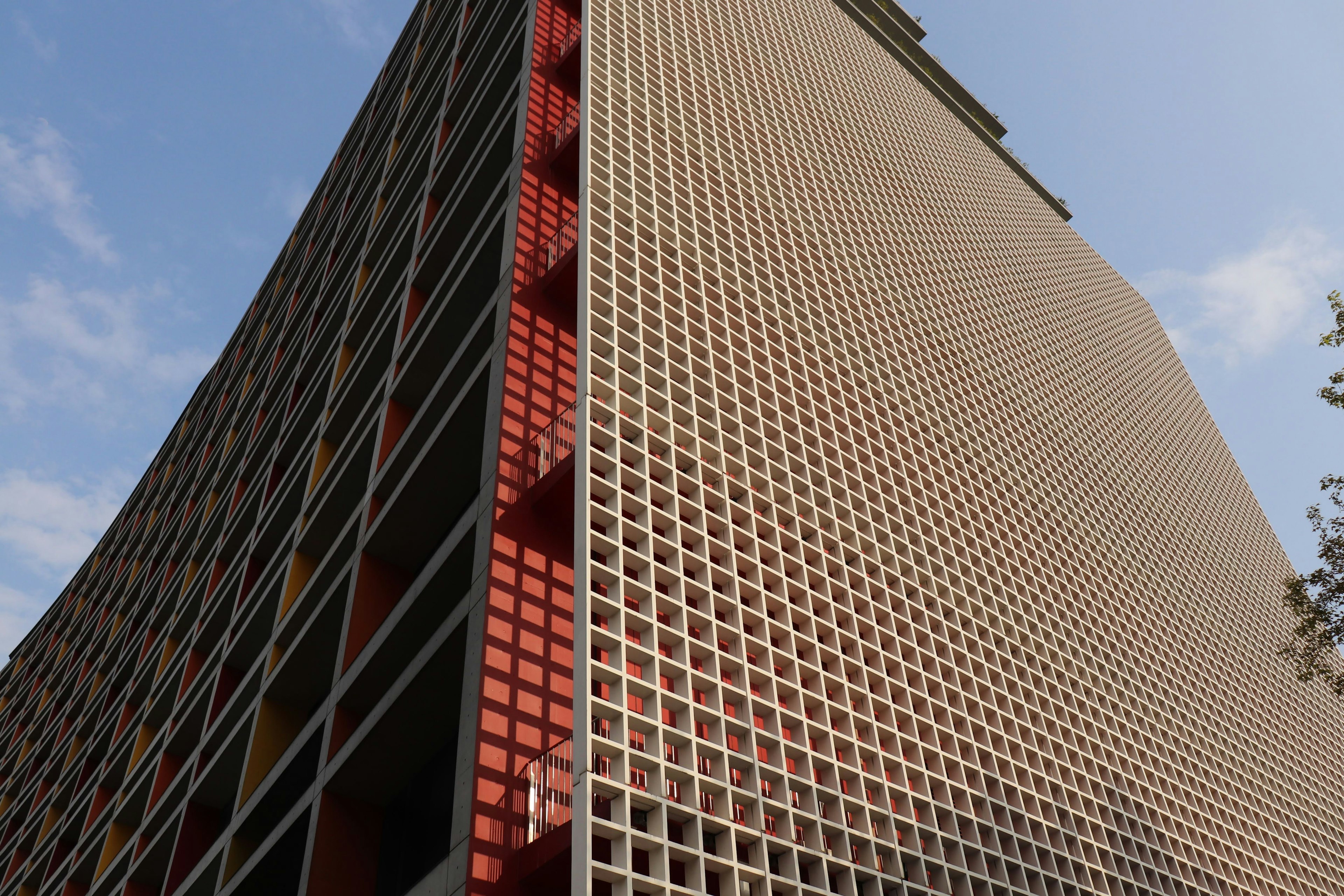 Façade d'un immeuble de grande hauteur avec un motif en grille et des accents rouges