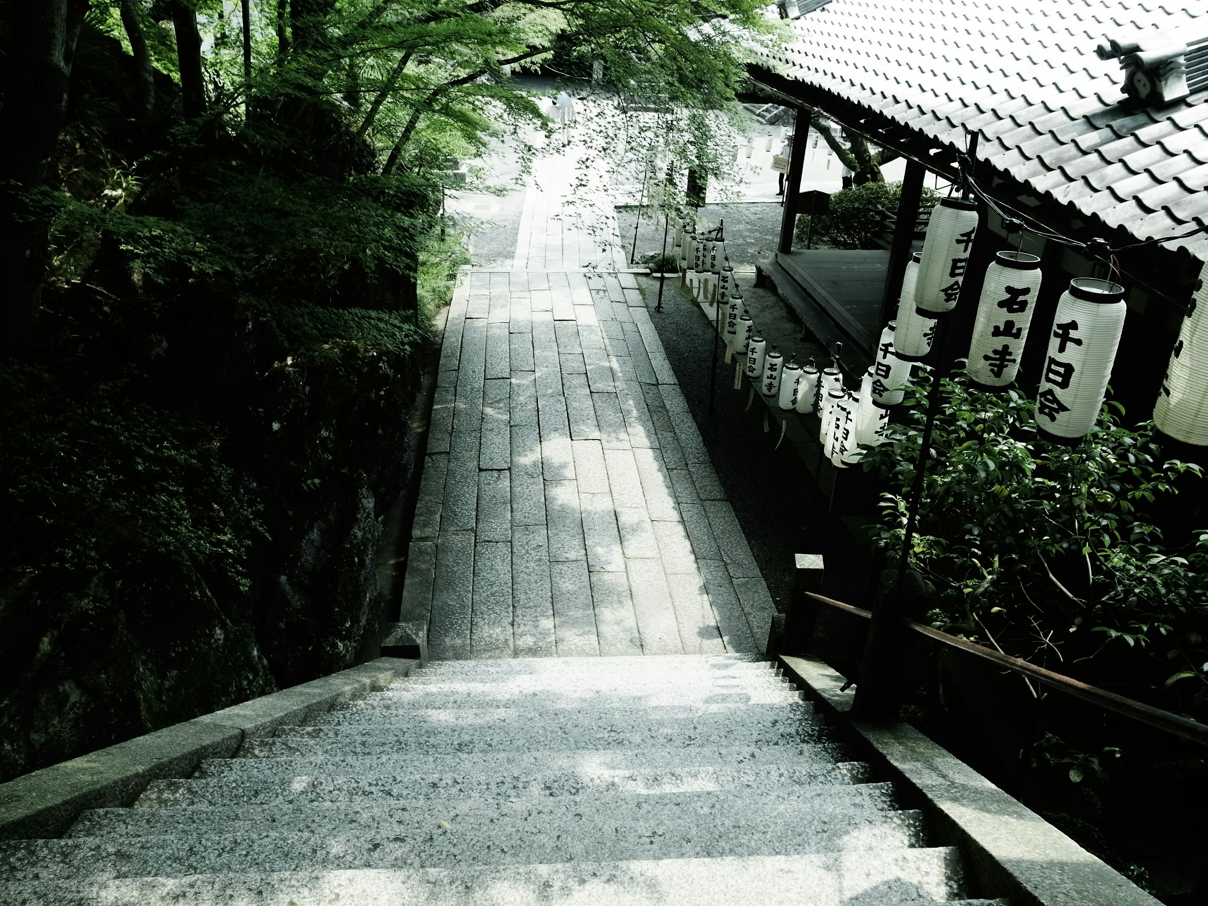 Scenic view of stone steps leading down towards a traditional building surrounded by greenery