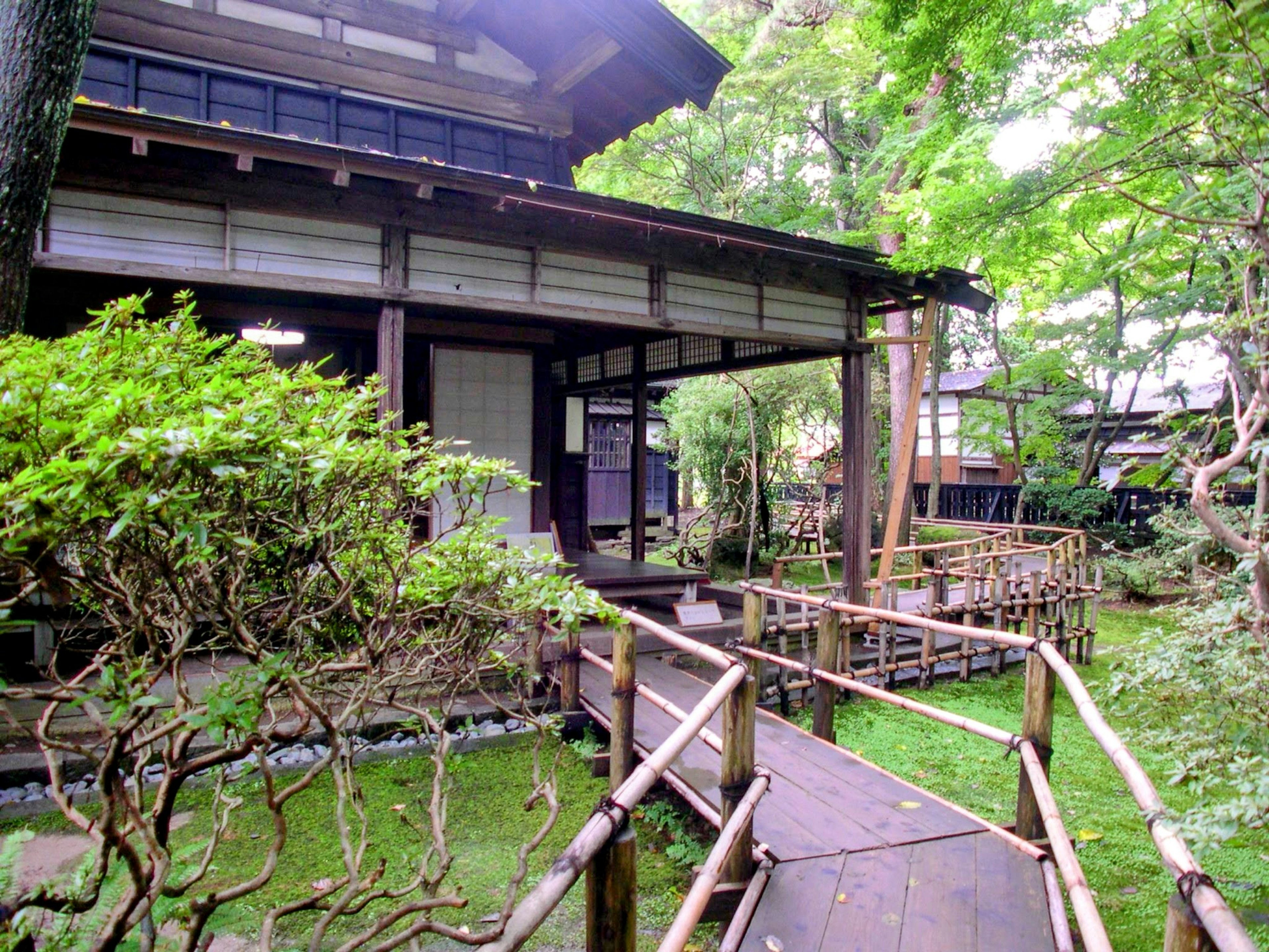 Casa japonesa tradicional y escena de jardín con vegetación y camino de bambú