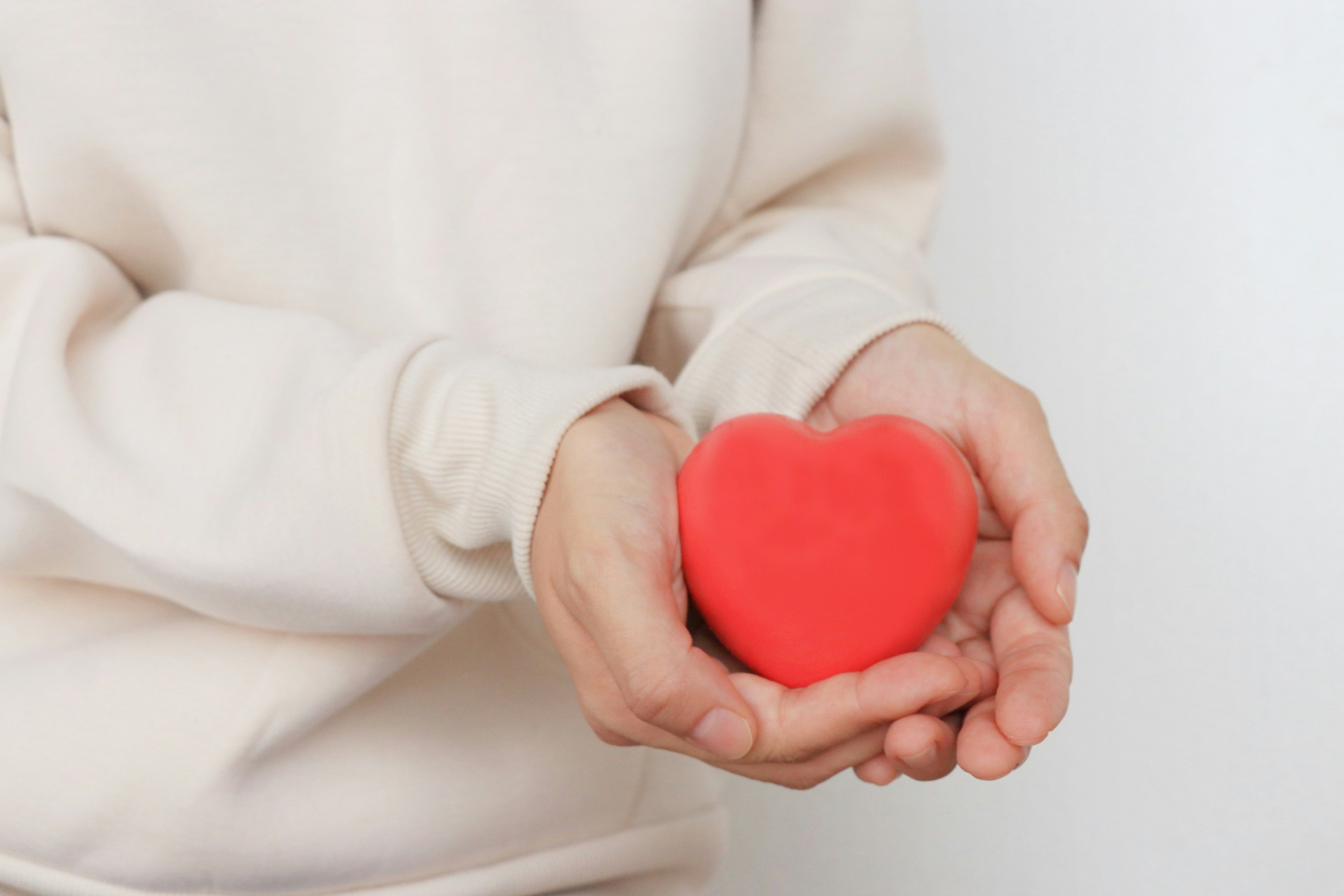 Mani che tengono un oggetto a forma di cuore rosso