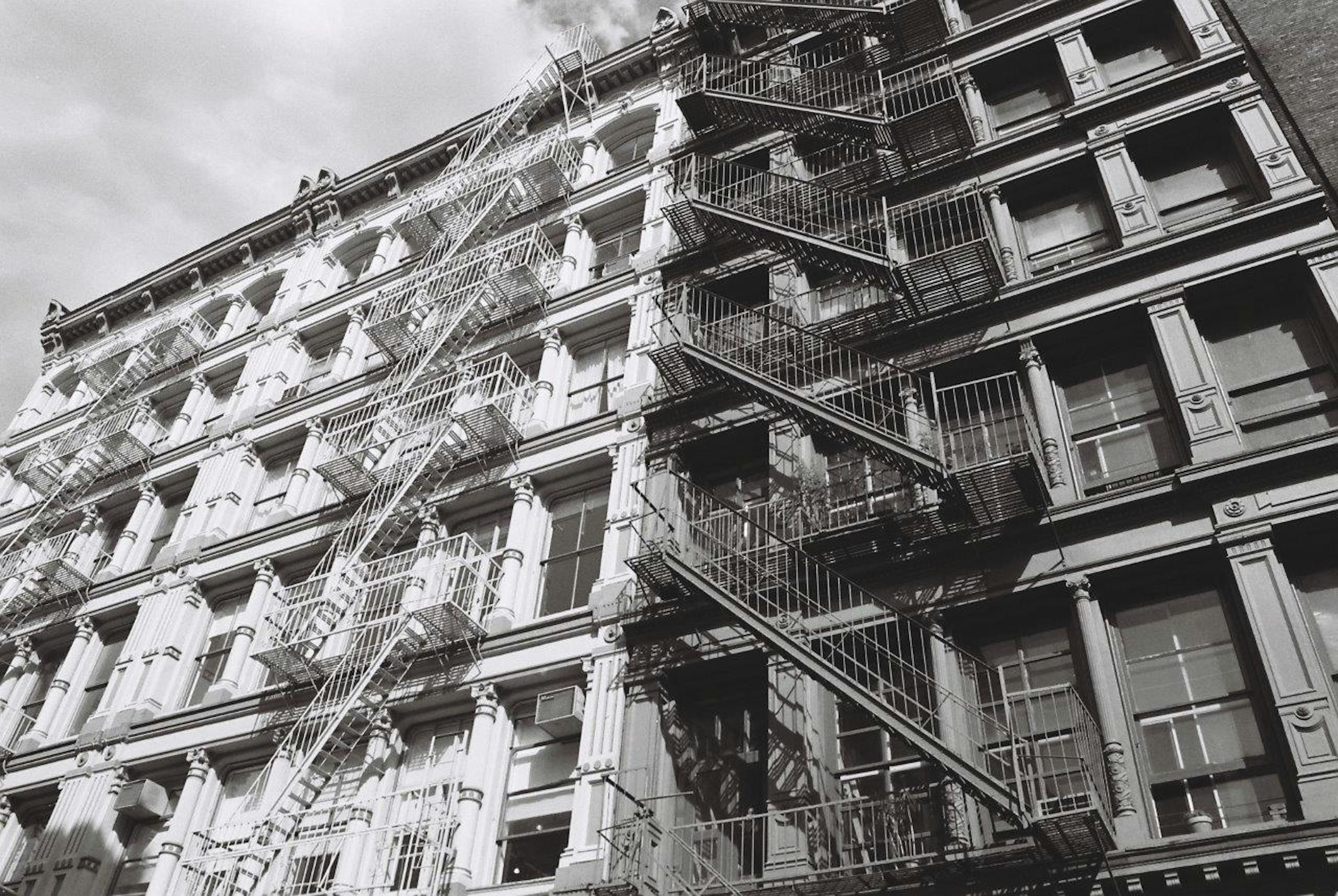 Façade de bâtiment en noir et blanc avec escaliers de secours en métal