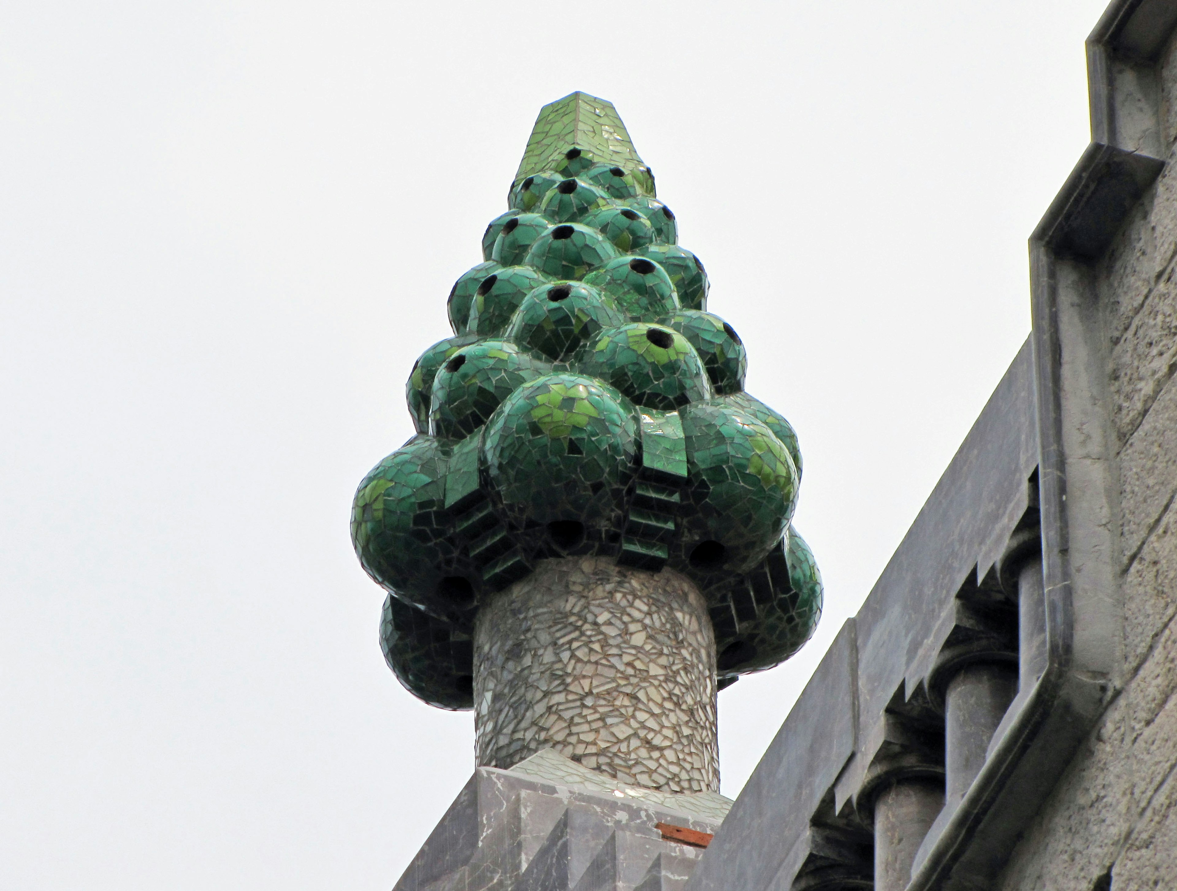 Sculpture décorative verte ressemblant à un cône de pin au sommet d'une tour