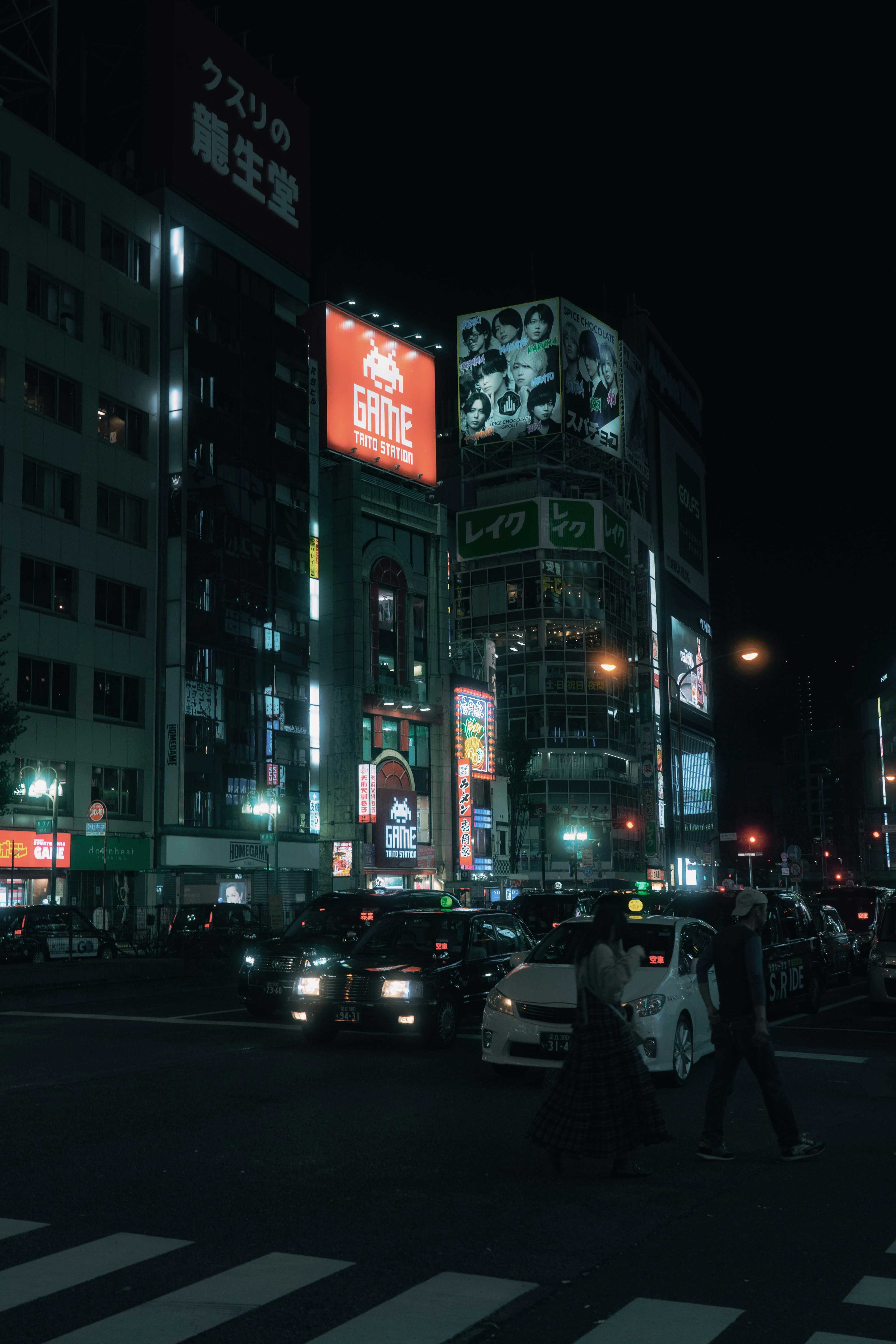 夜の都市風景に明るい広告と車両が行き交う交差点