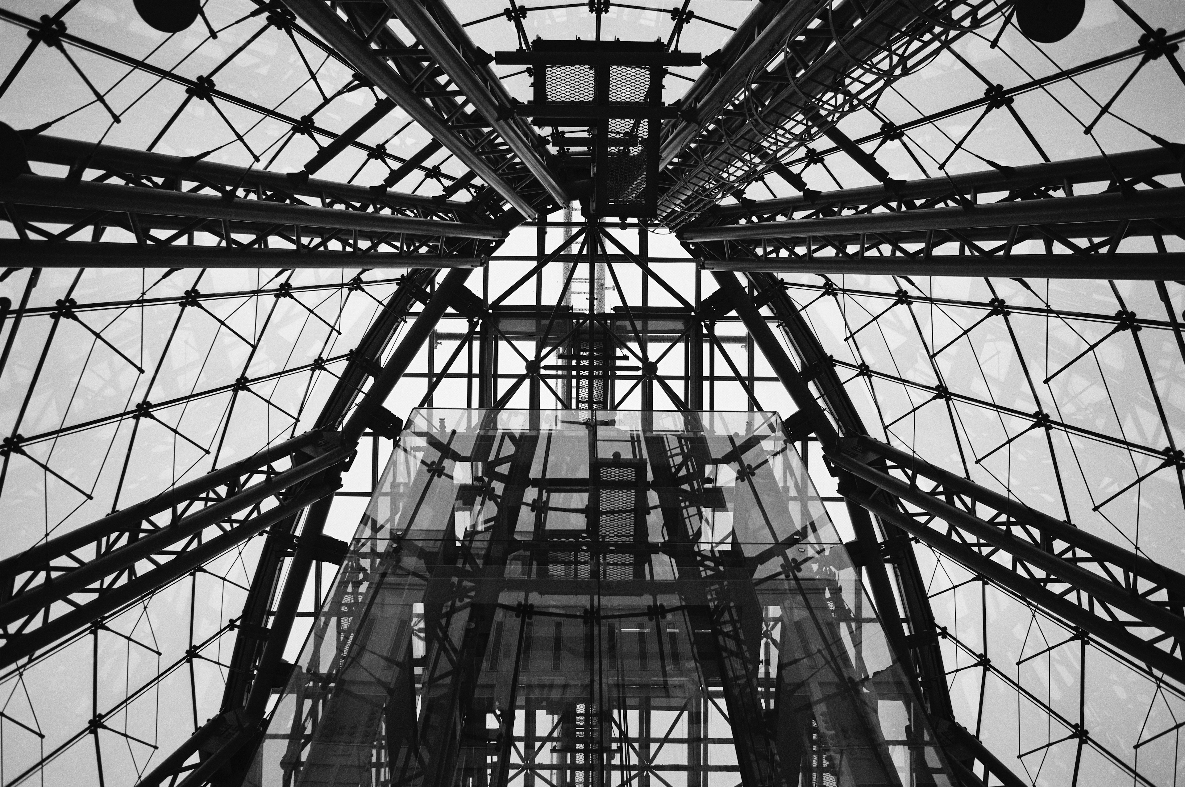 View looking up at a black and white structure featuring metal frames and glass details