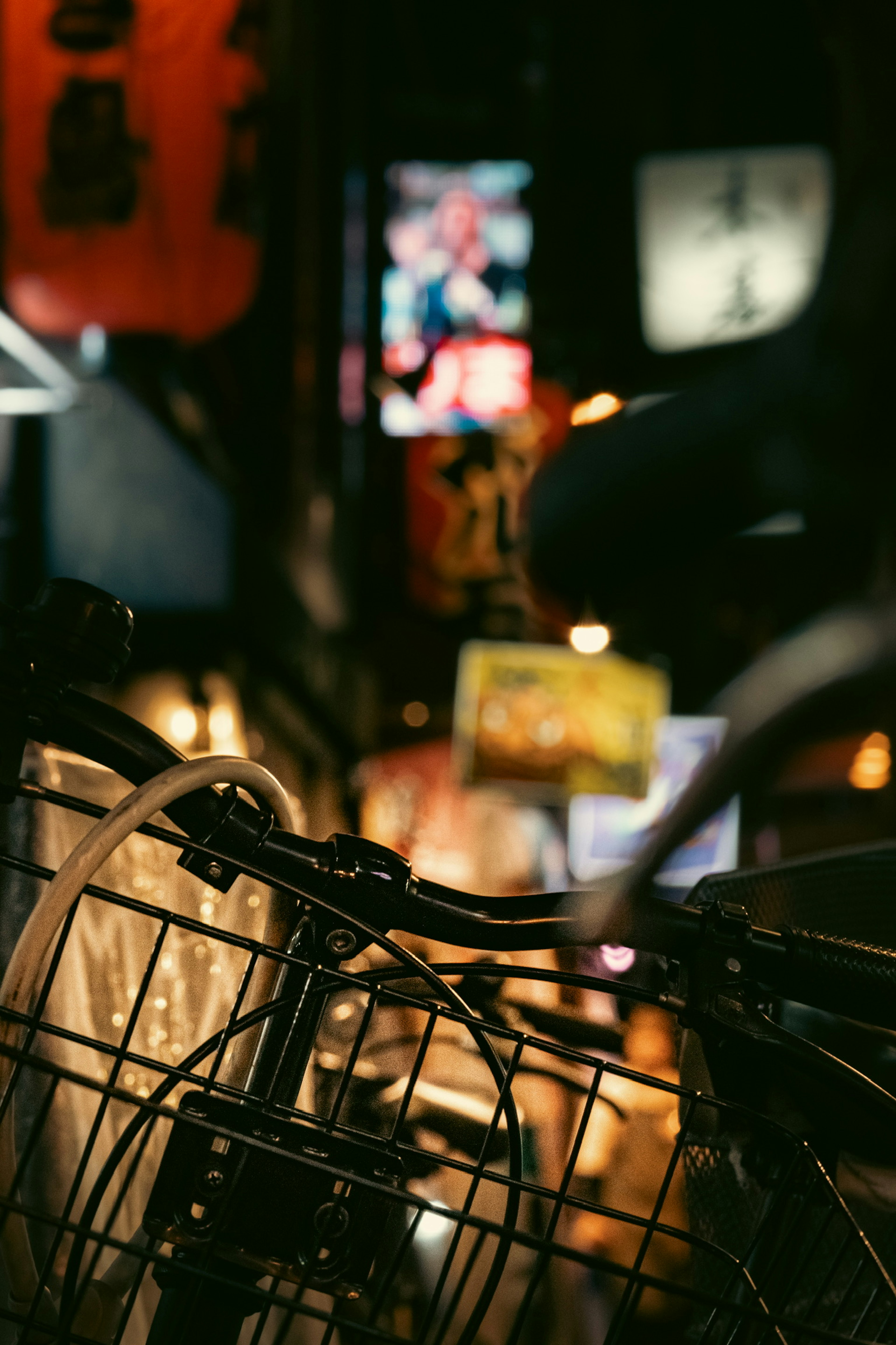 Foreground of a bicycle with bright neon signs in a night street