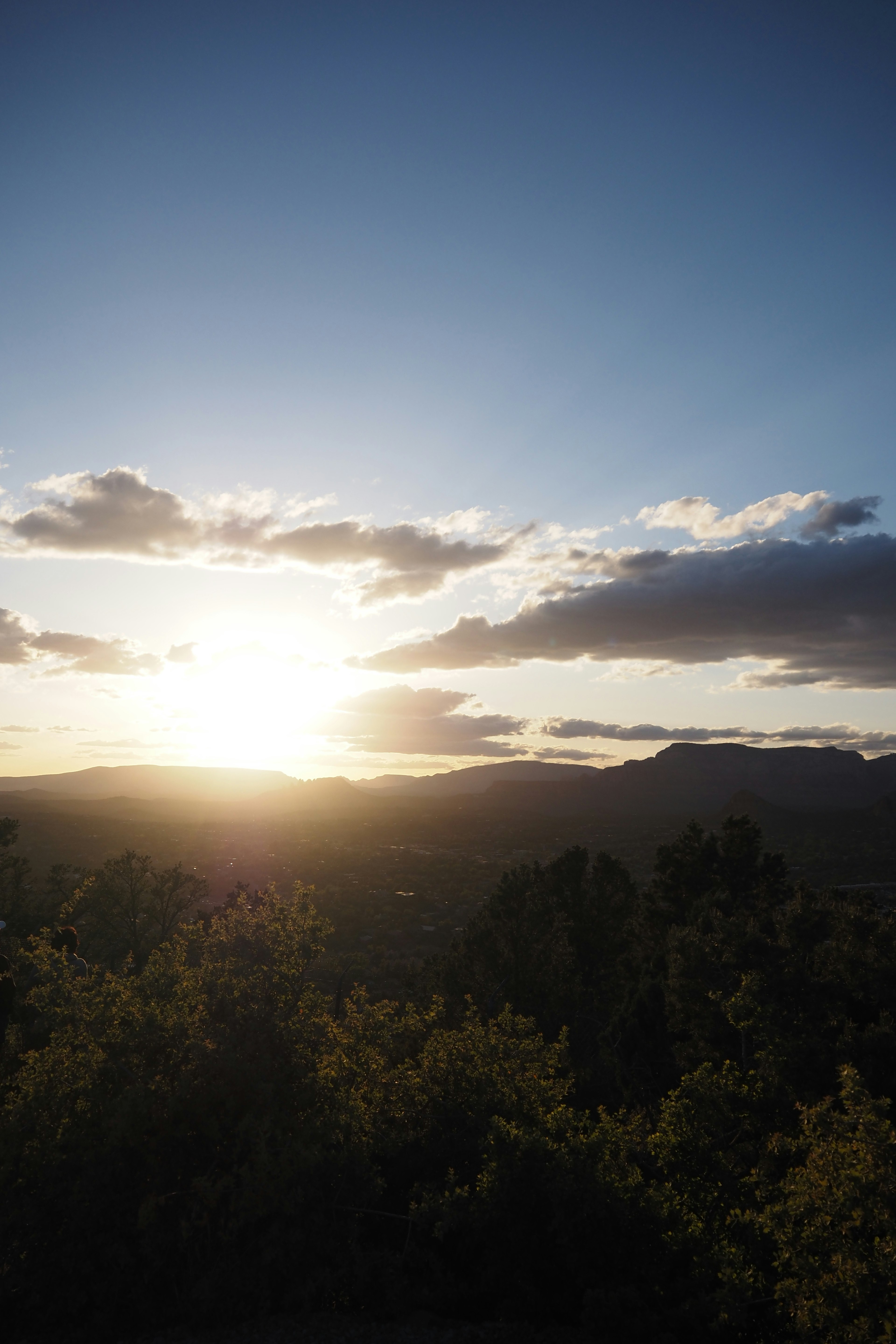 Sonnenuntergang über Bergen mit üppigem Grün und blauem Himmel