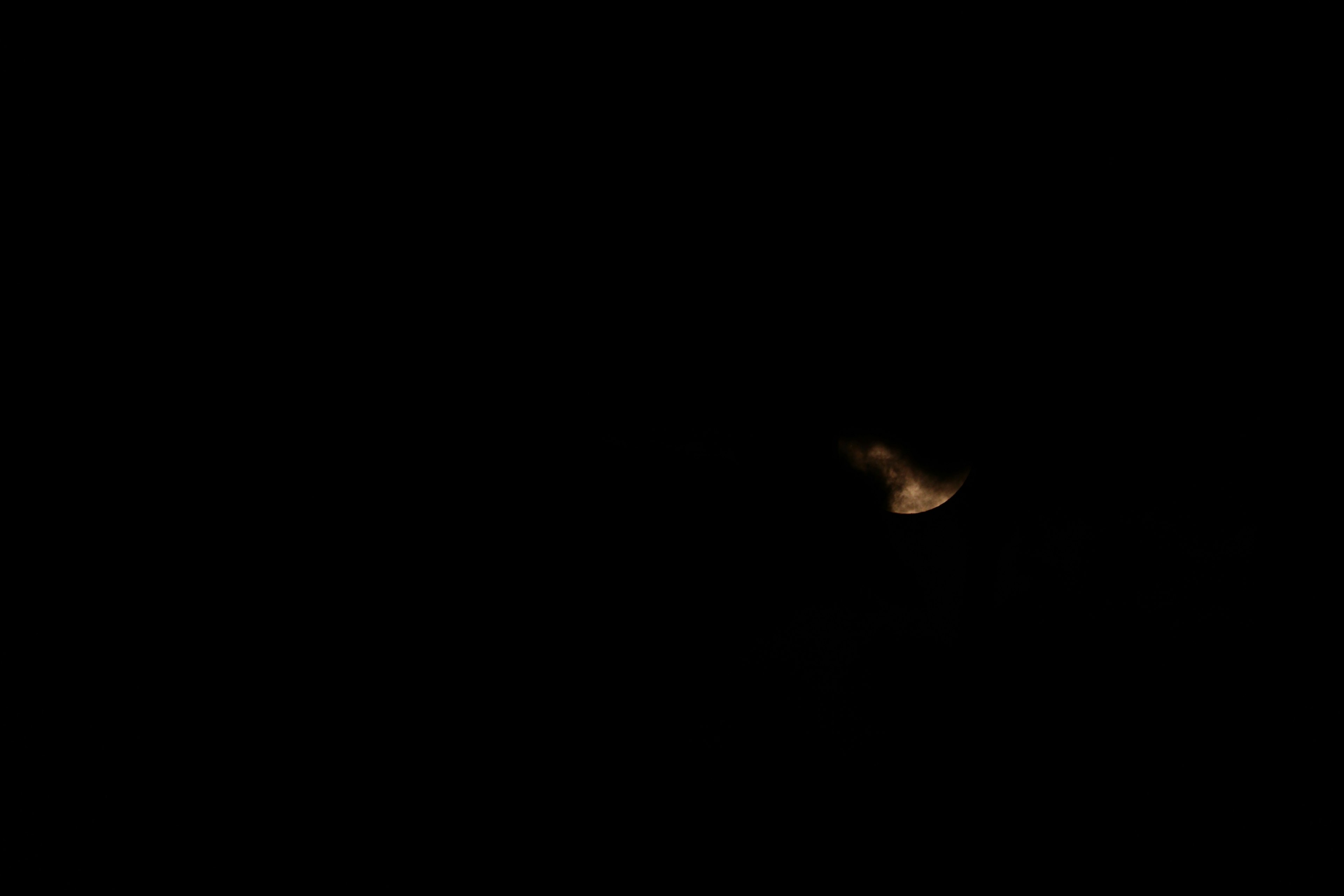 Una luna parcialmente visible sobre un fondo oscuro