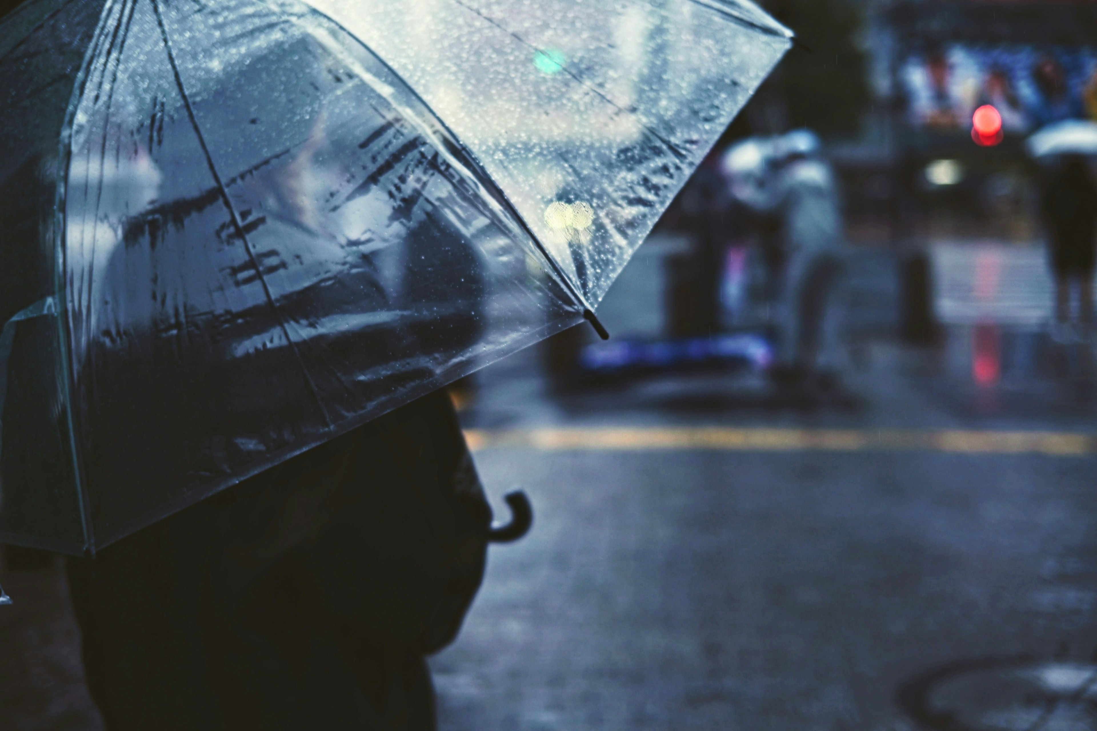 Silhouette d'une personne tenant un parapluie transparent sous la pluie