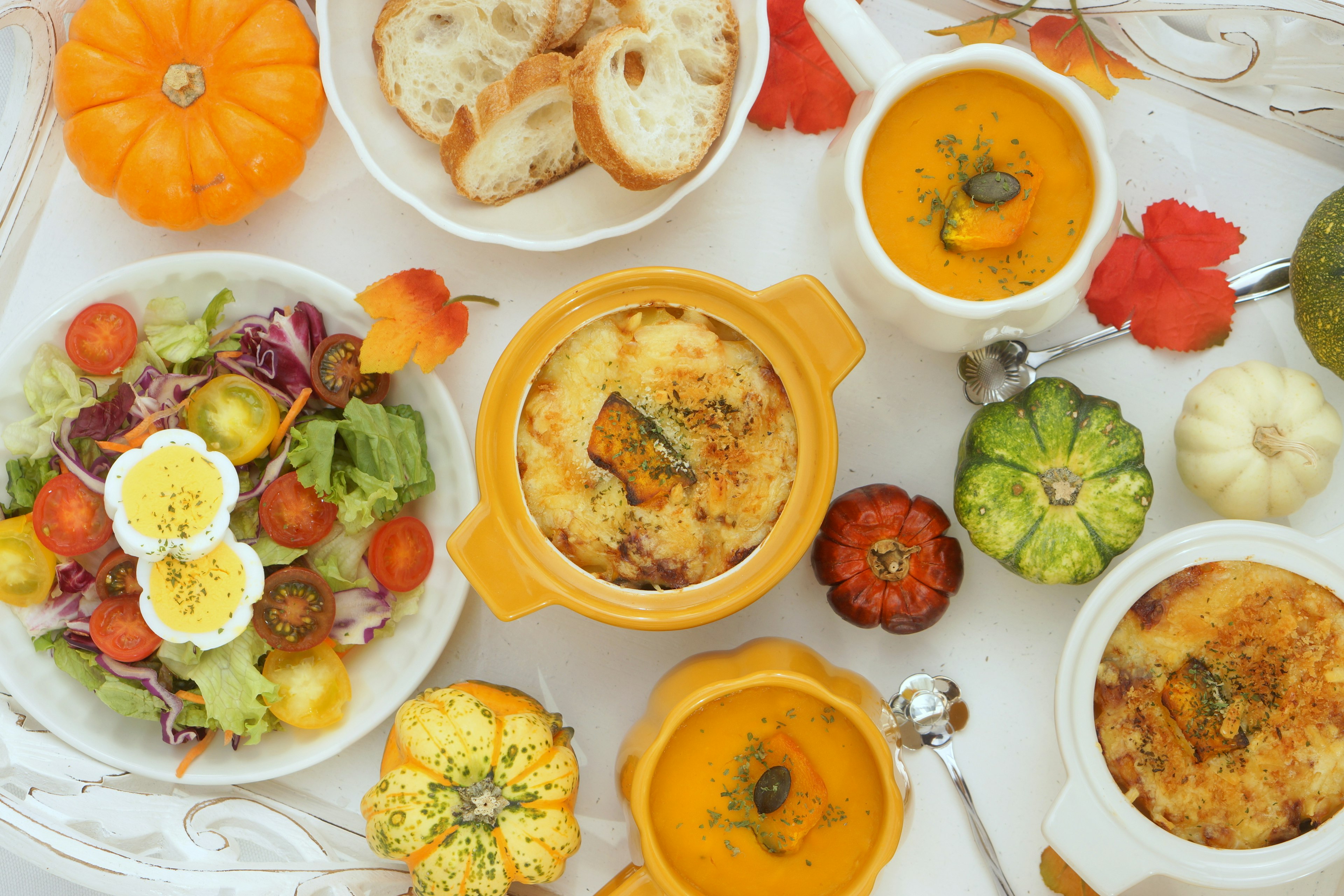 Una exhibición colorida de calabazas y ensalada con sopa cremosa y platos horneados en una mesa de comedor