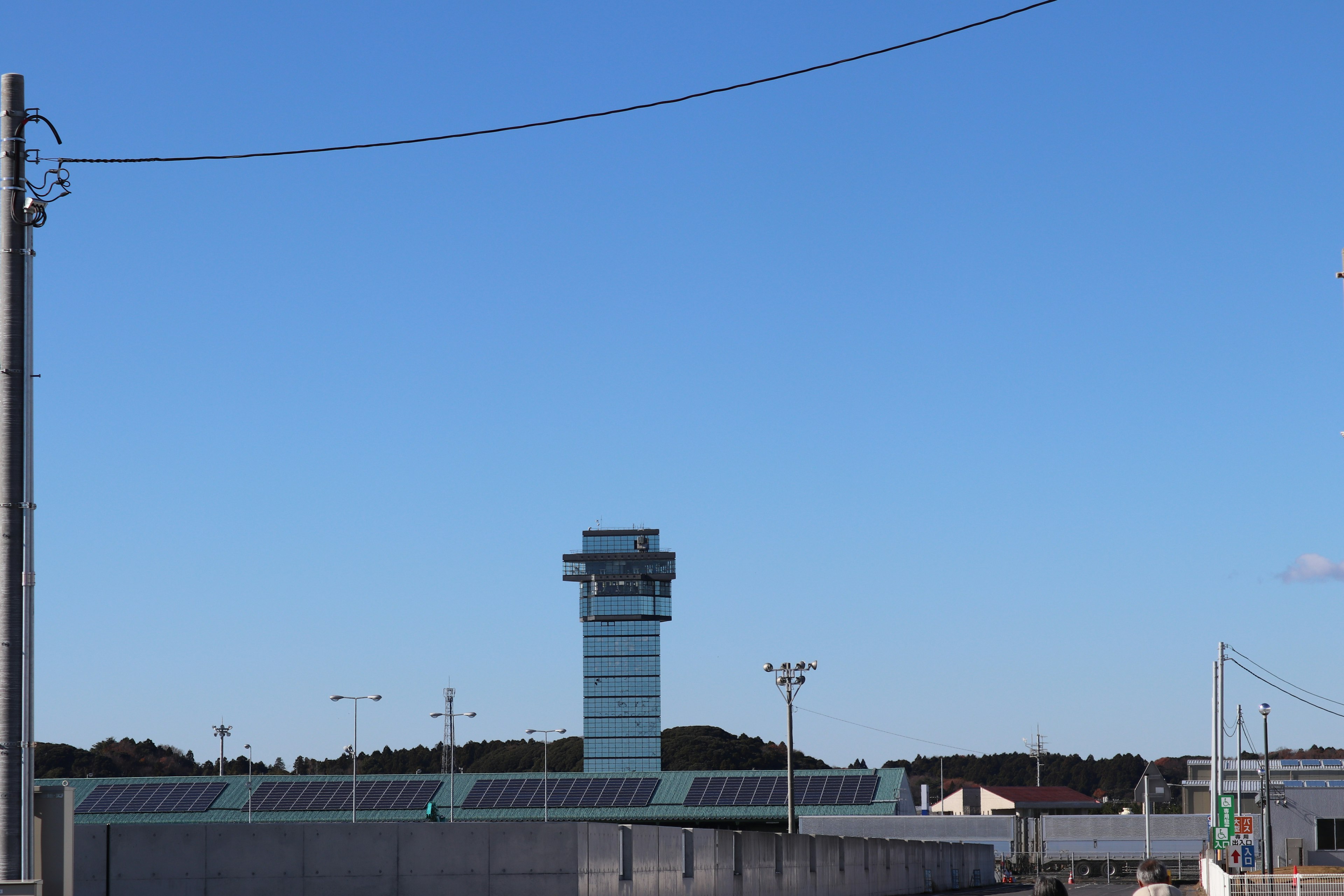 Torre de control de aeropuerto bajo un cielo azul claro con edificios circundantes