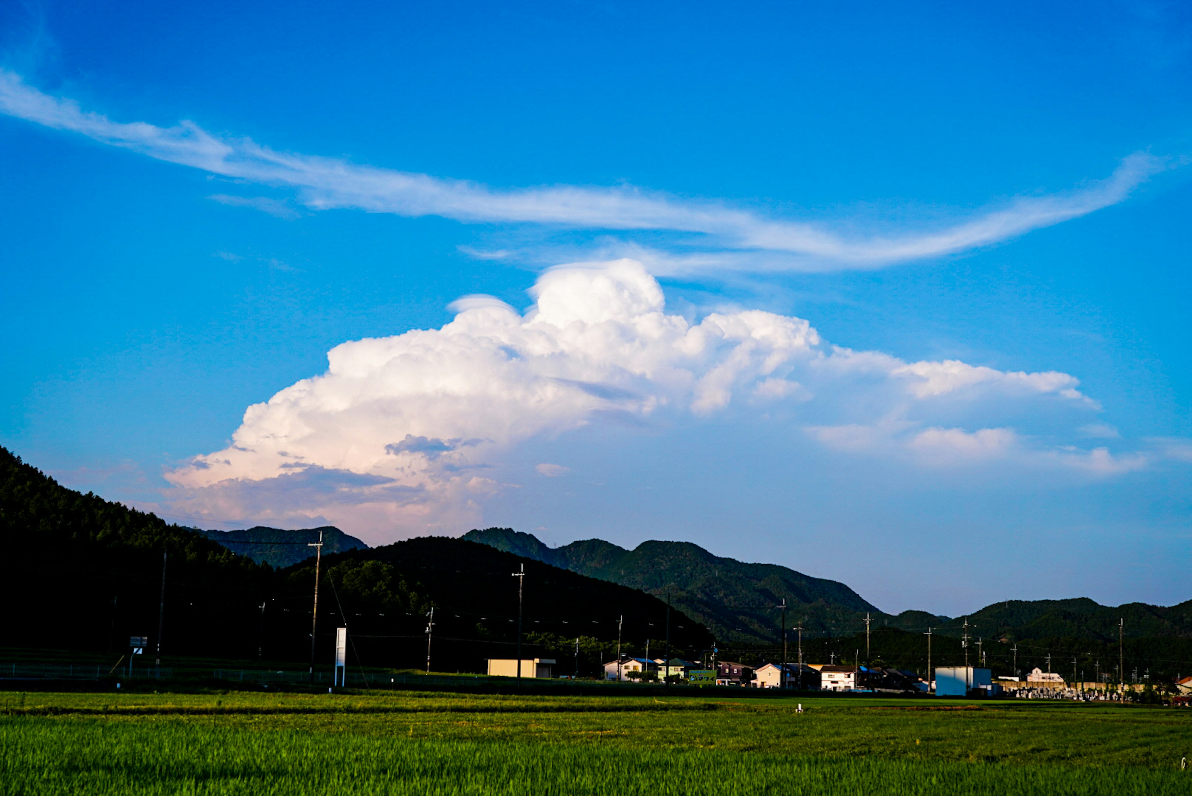 青空と白い雲が広がる風景 緑の田んぼと山々が見える