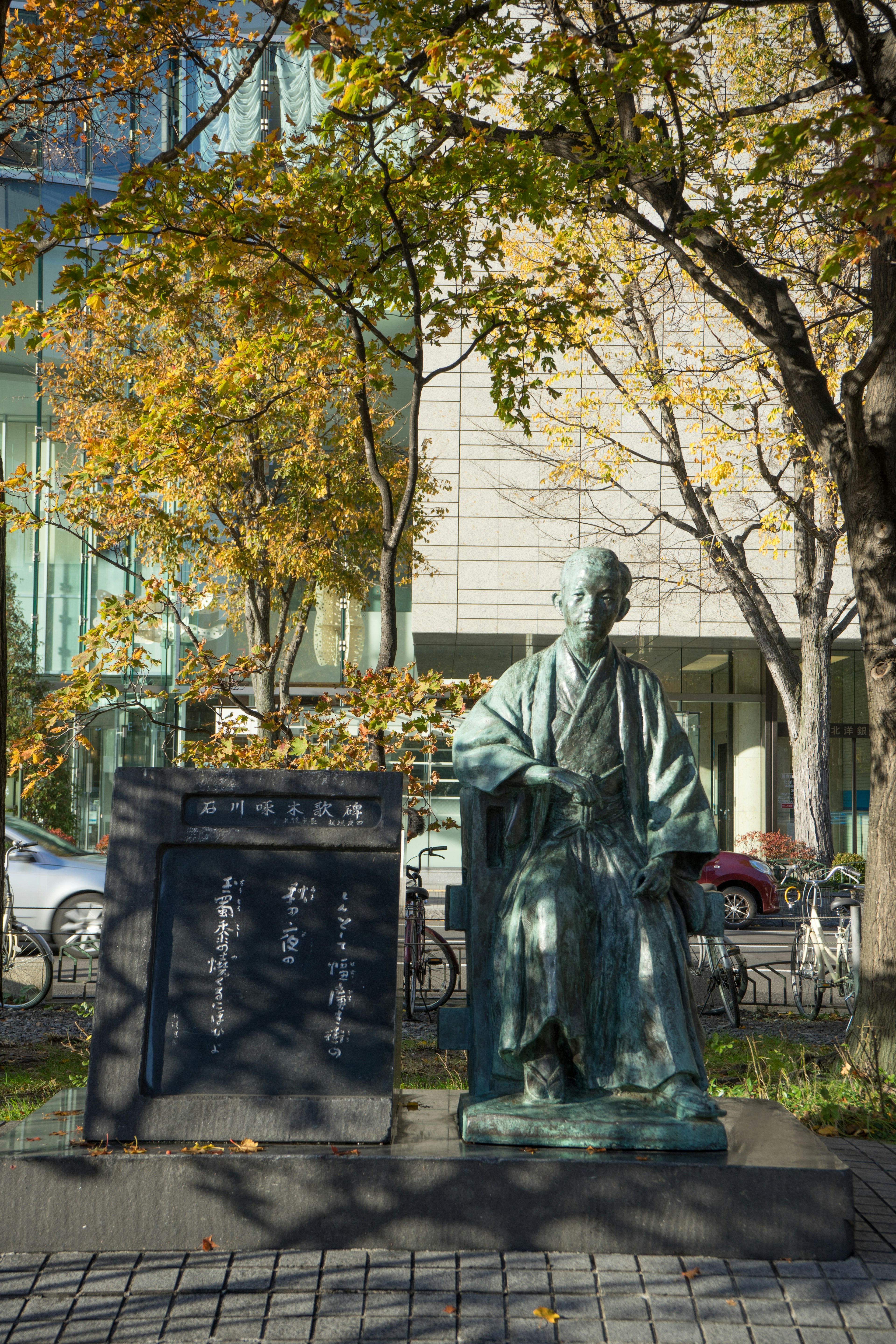 Bronze statue in autumn scenery with modern building in background