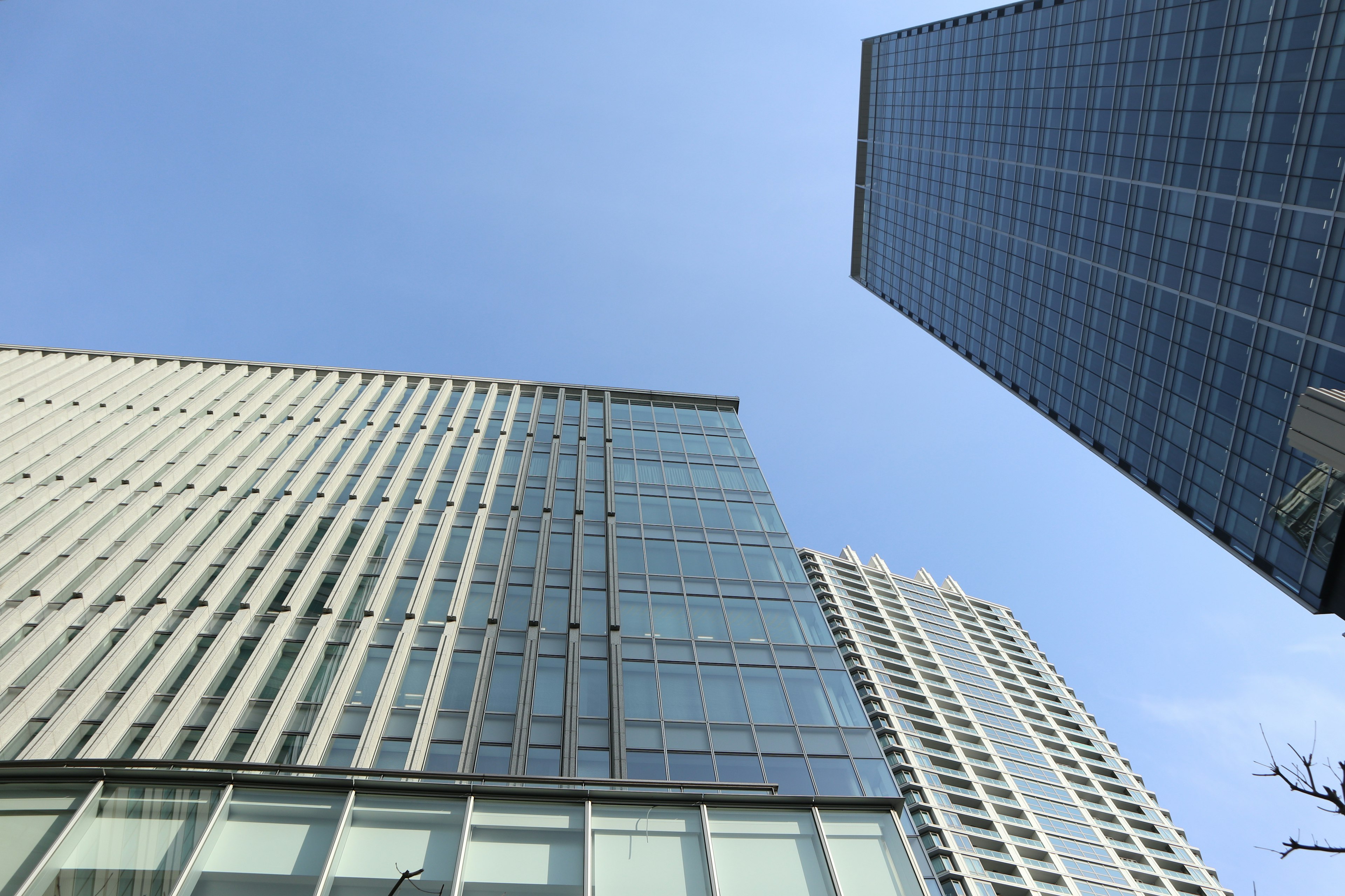 View looking up at tall buildings against a clear blue sky