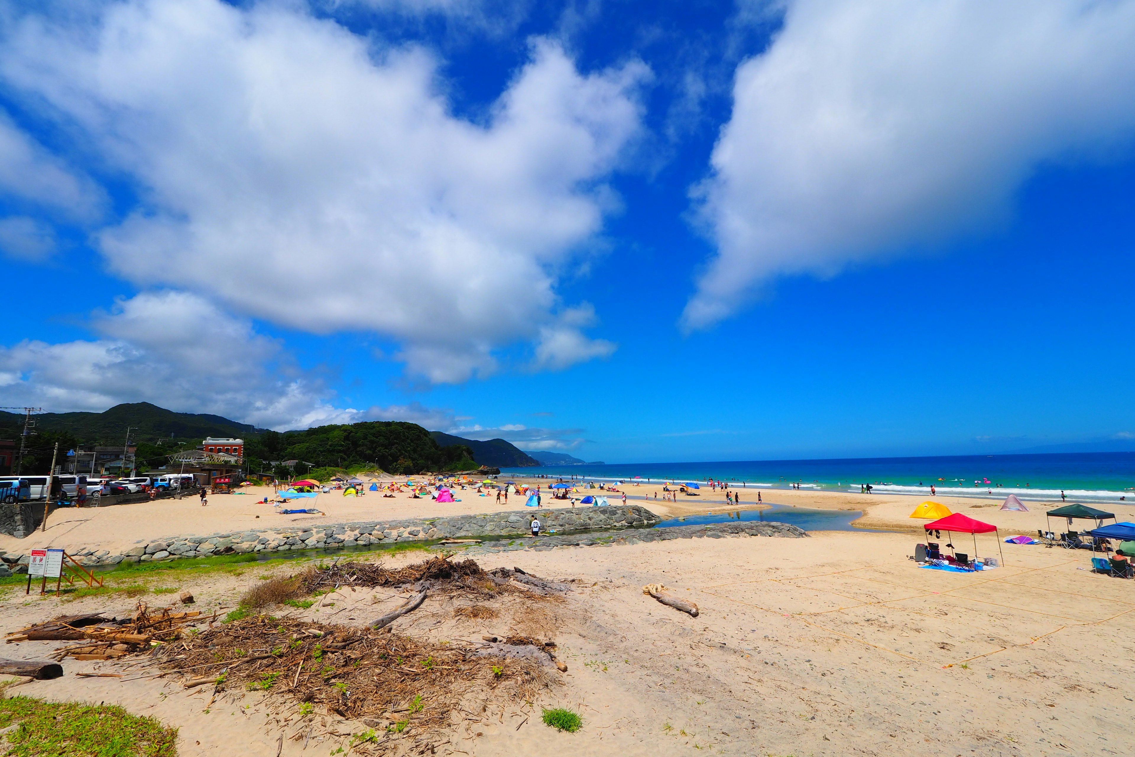 Pemandangan pantai dengan langit biru dan awan putih Payung berwarna-warni tersebar di pasir