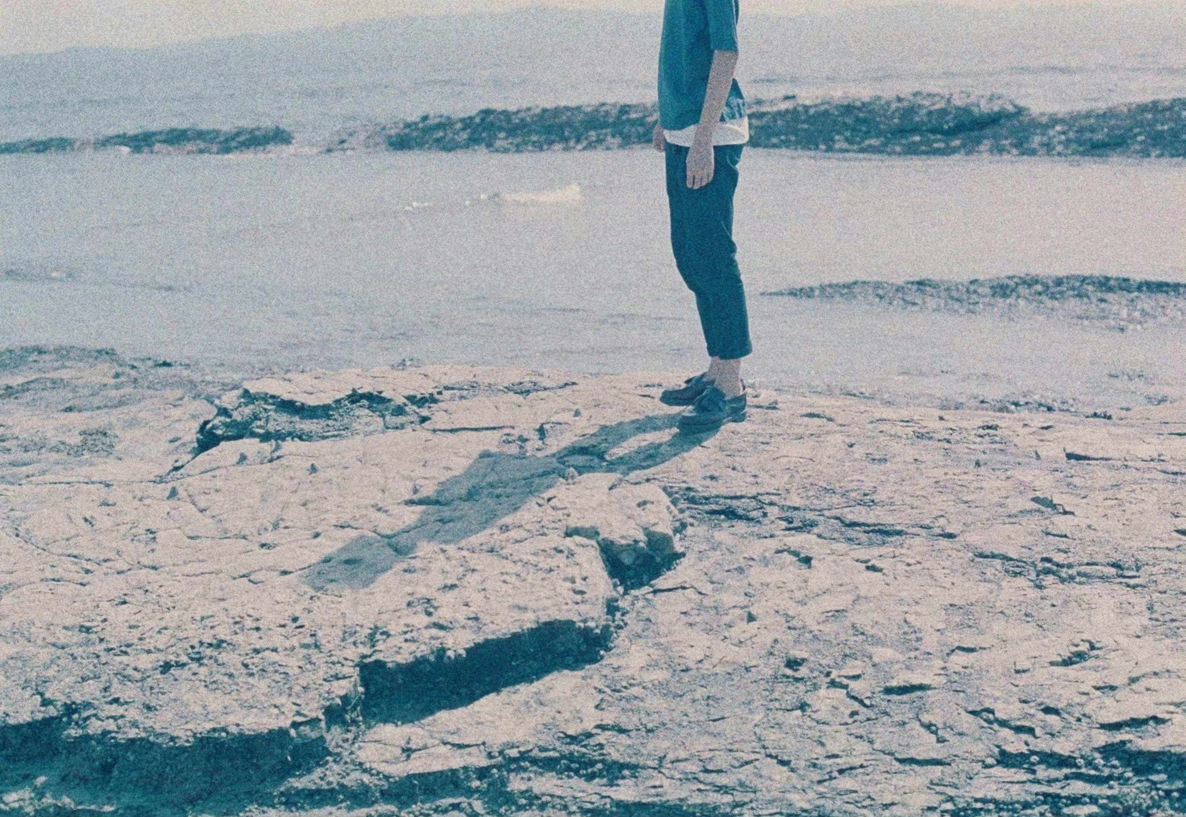 Personne debout sur un rivage rocheux avec ombre et océan bleu