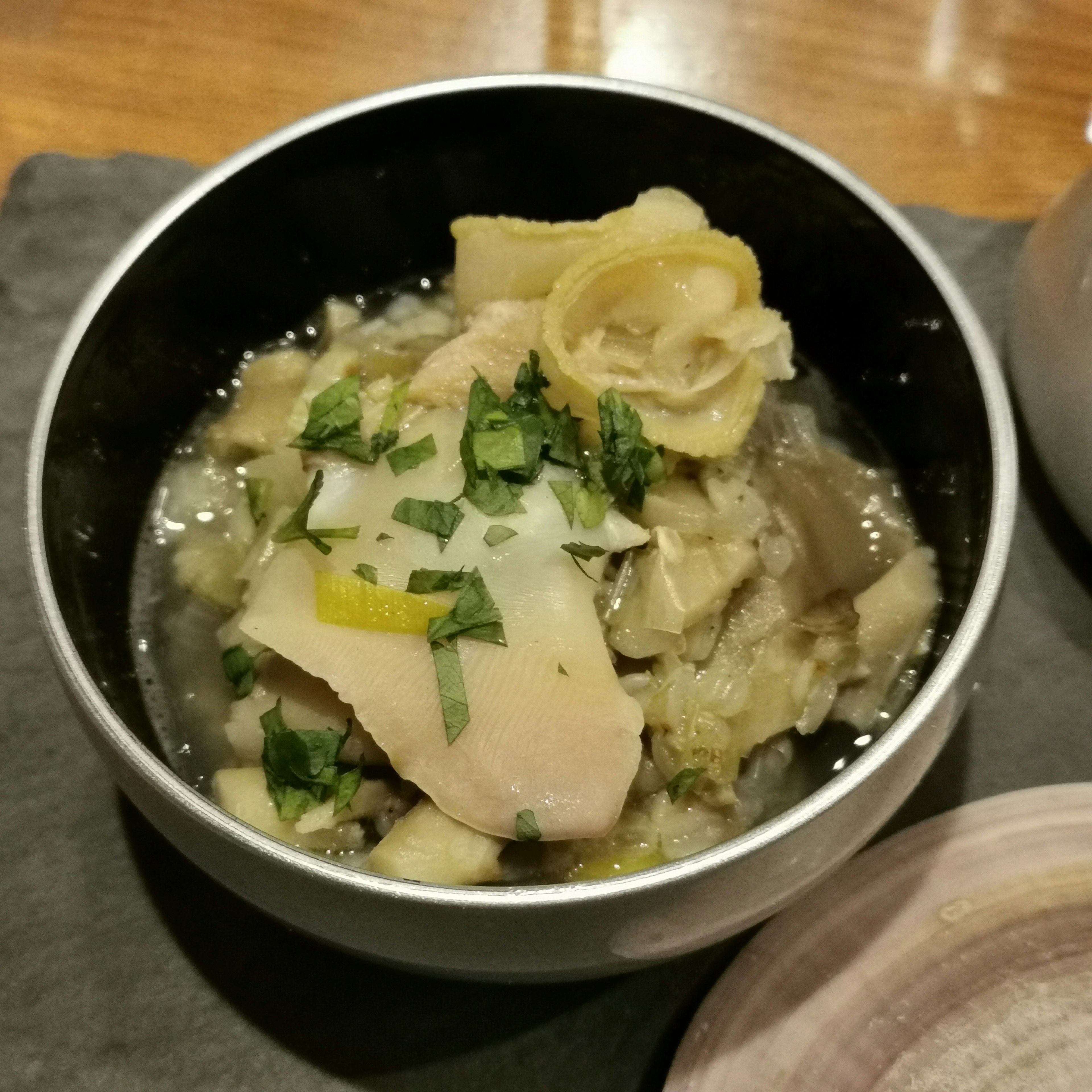 Tazón de sopa de pollo y verduras decorado con limón y hierbas