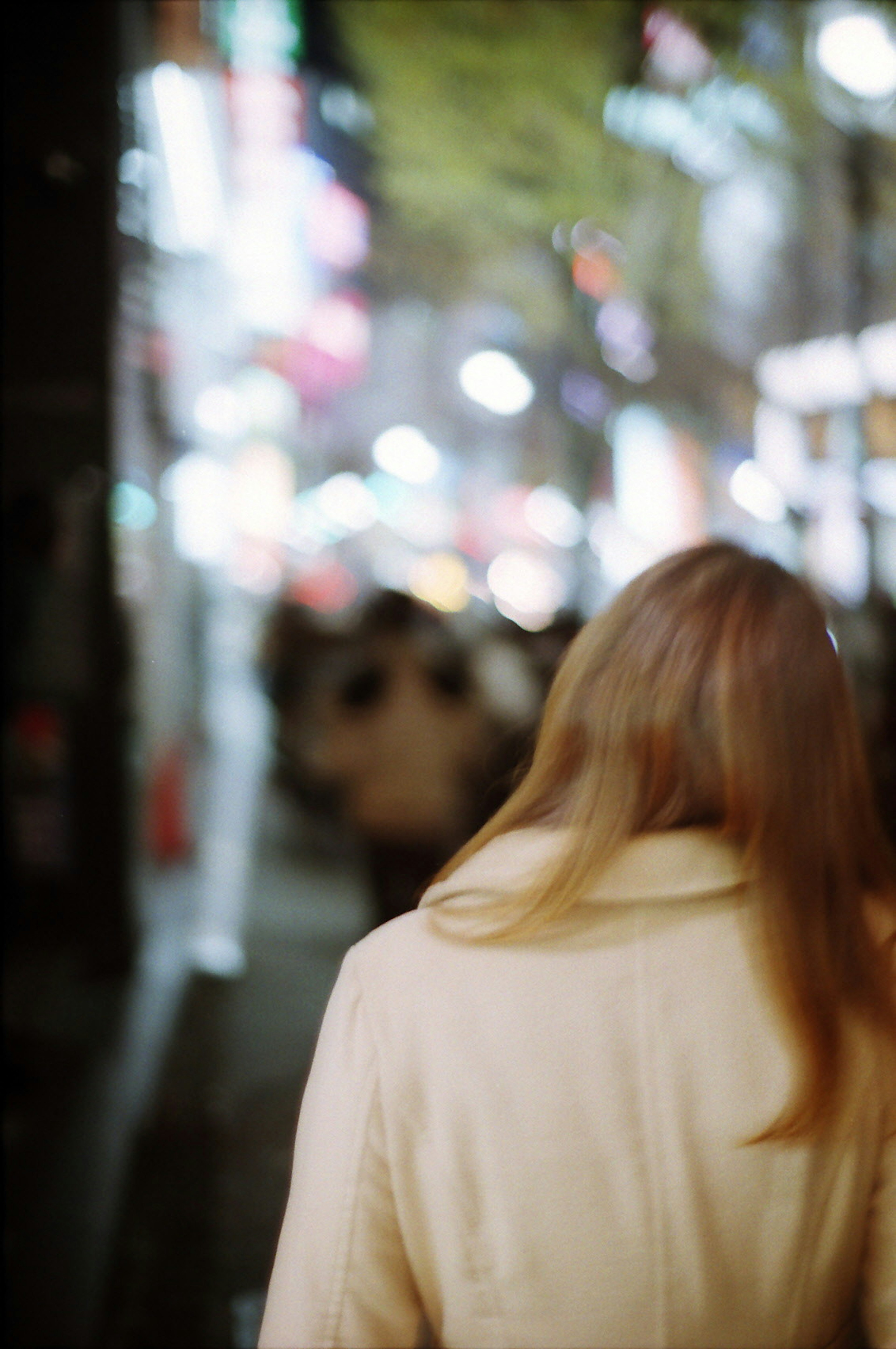 Foto di una donna che cammina nella città di notte con luci al neon colorate sfocate sullo sfondo