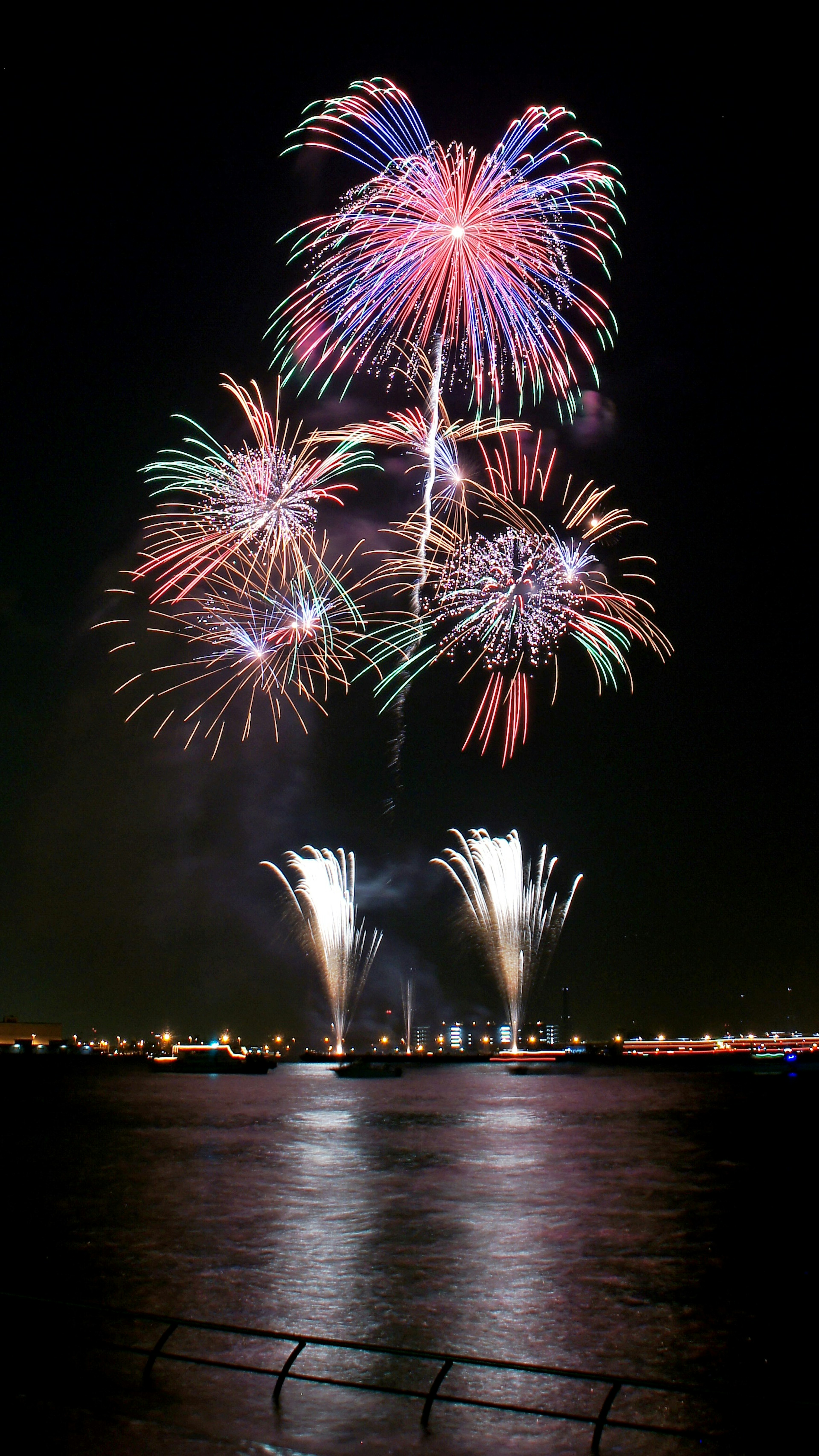 Spectacle de feux d'artifice colorés au-dessus de l'eau la nuit