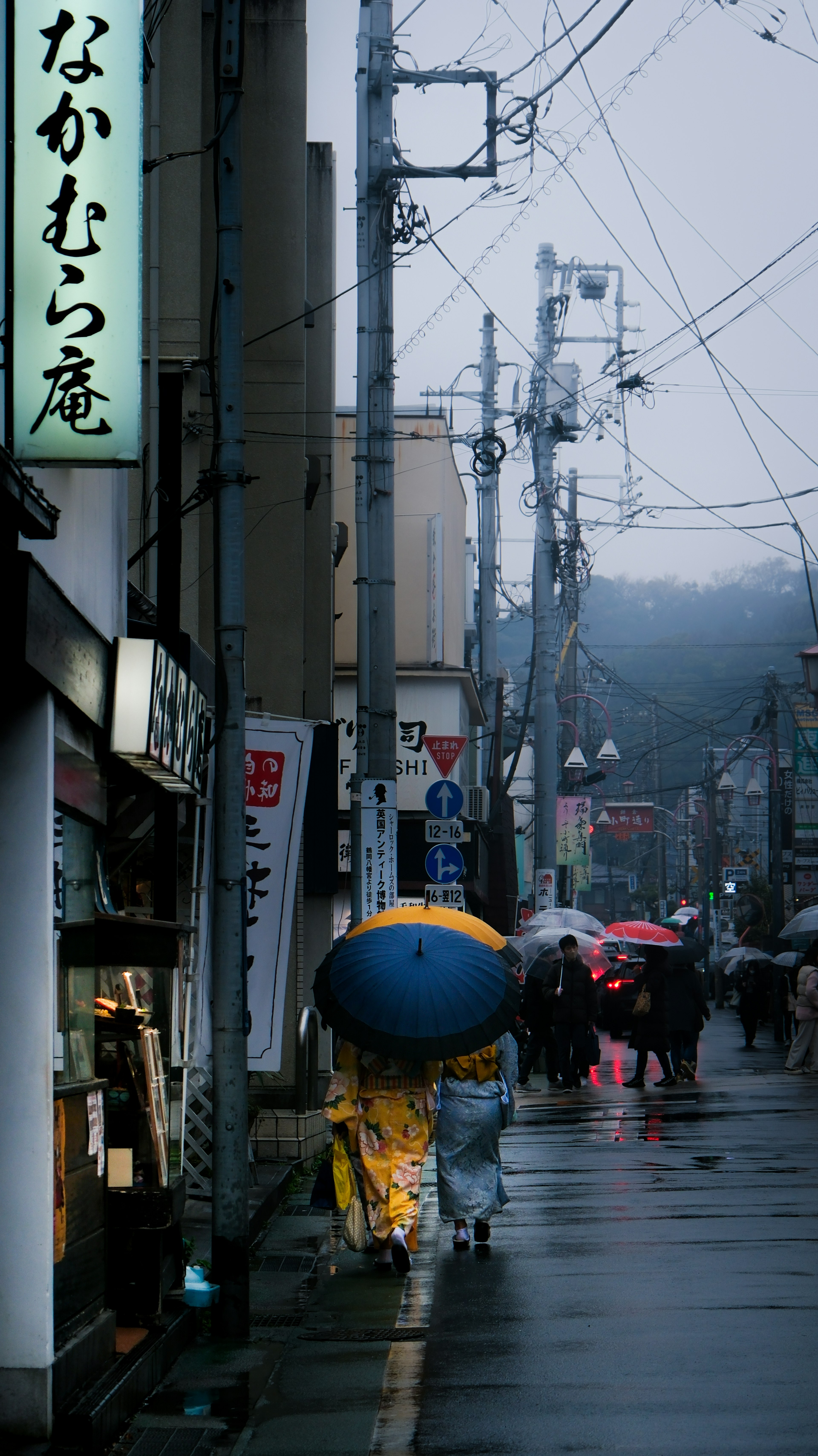 雨の中を歩く人々と青い傘の風景