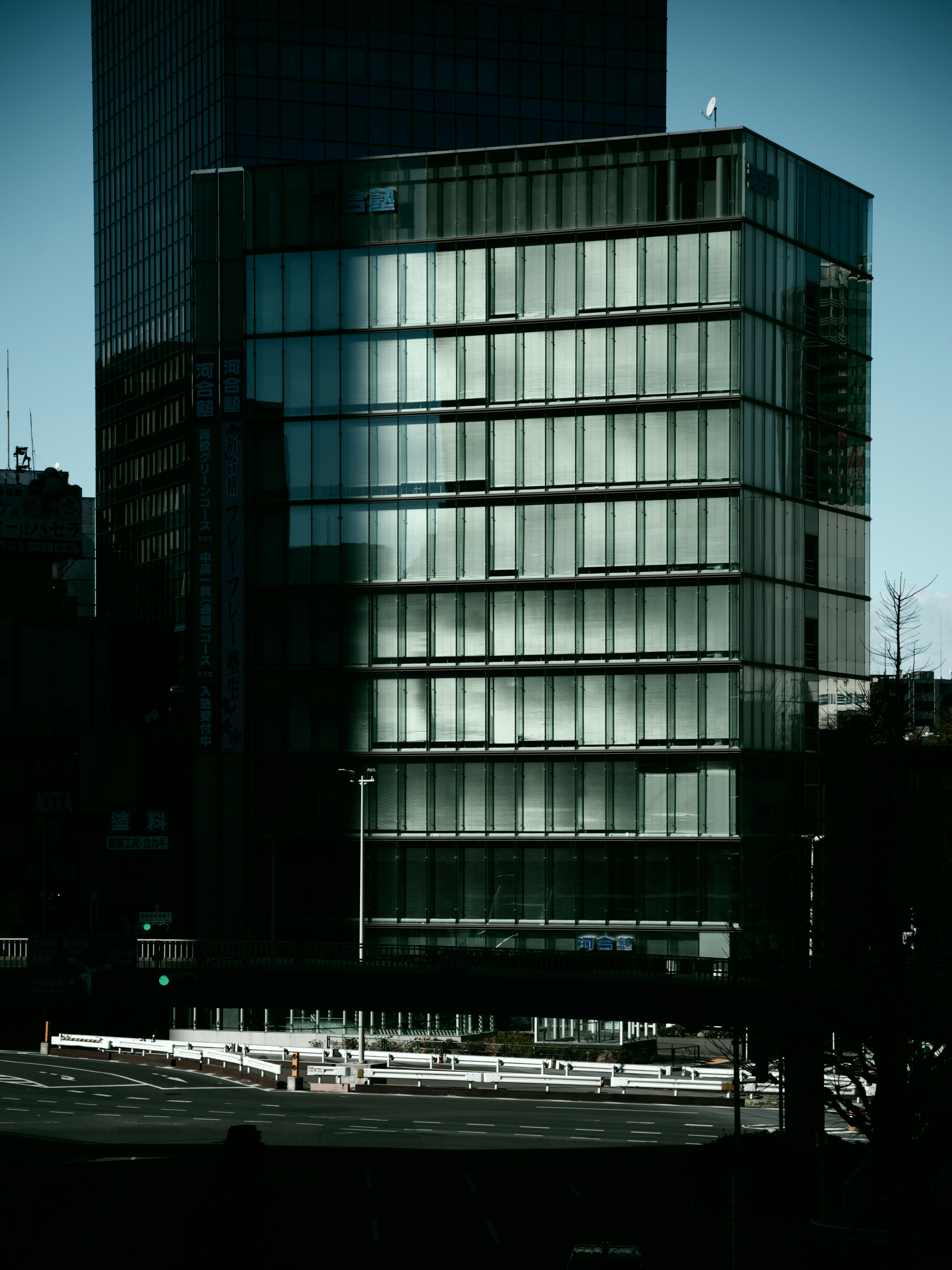 Bâtiment moderne en verre dans l'ombre avec un arrière-plan urbain