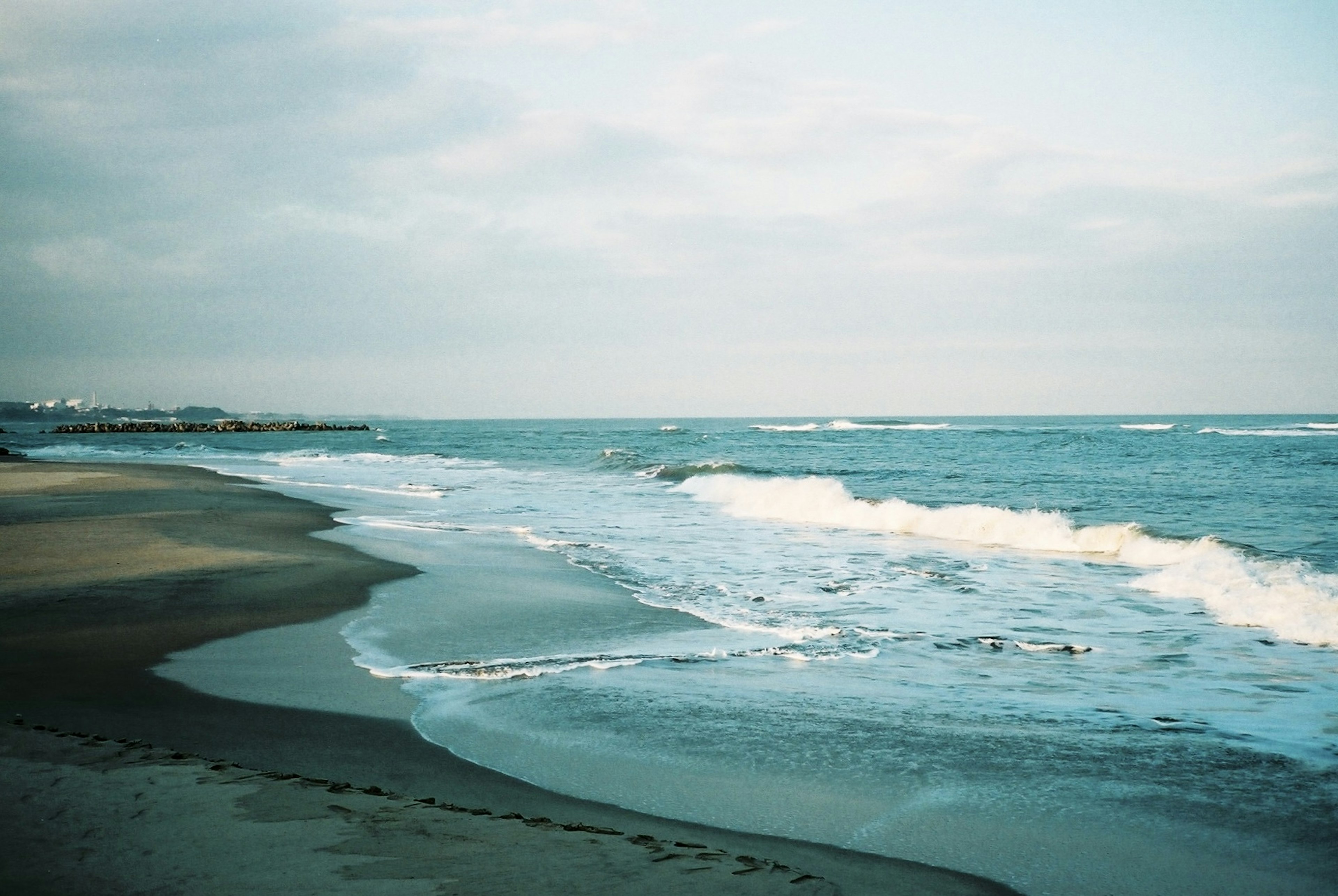 ทิวทัศน์ชายหาดสงบกับคลื่นนุ่มและท้องฟ้าหมอก