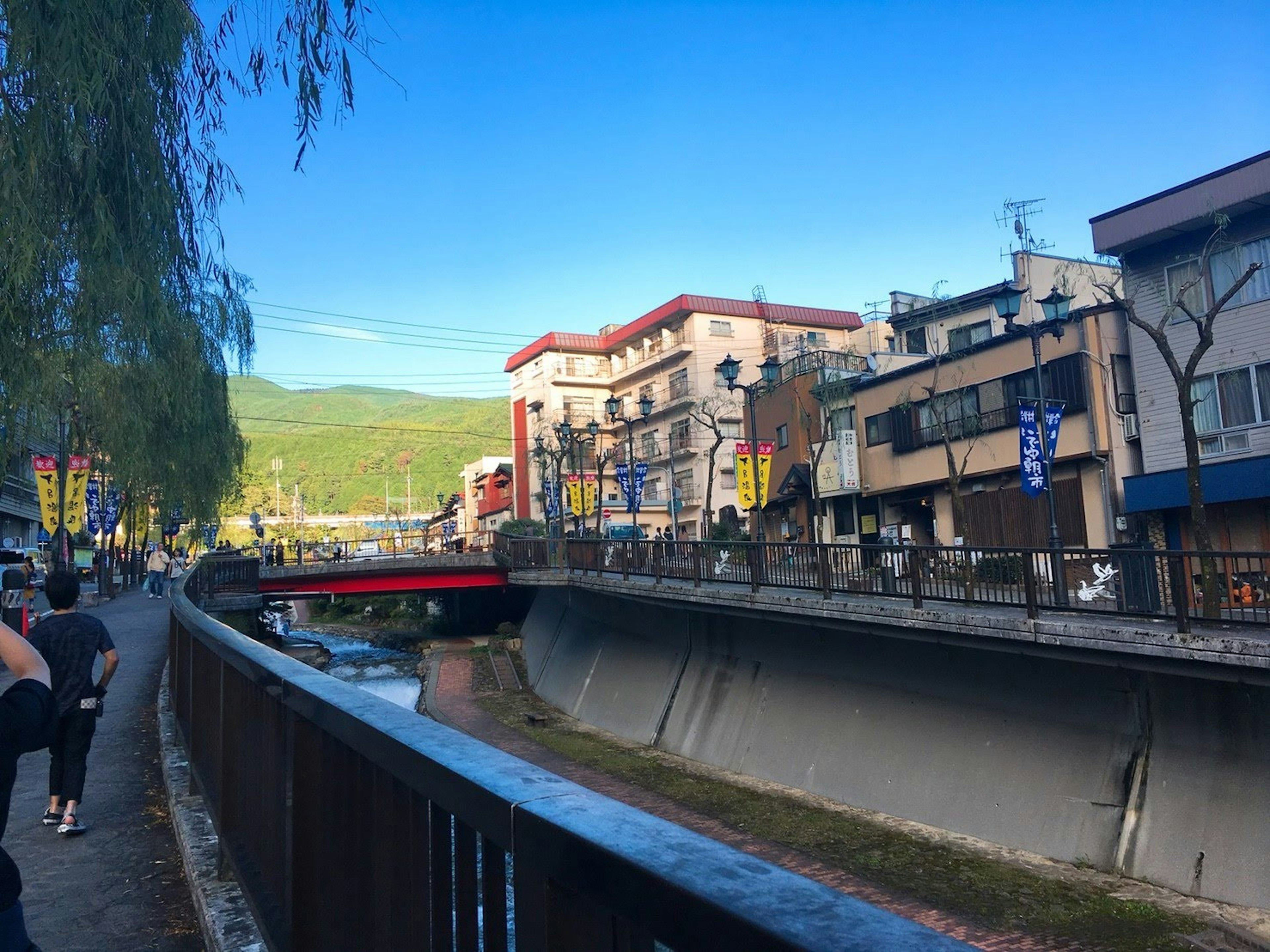 Vista panoramica lungo il fiume con un ponte rosso e negozi