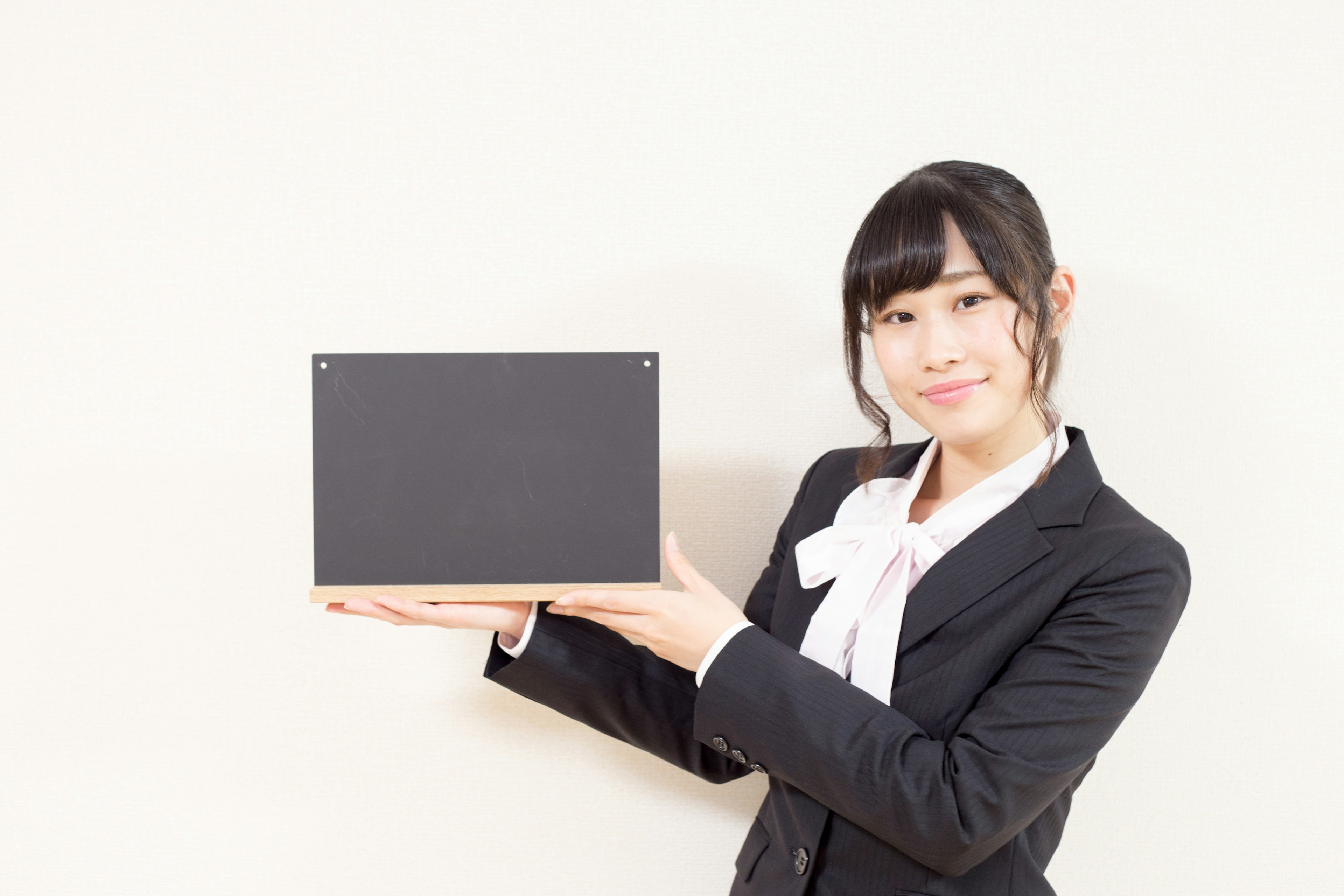 A woman in a business suit holding a black box and smiling