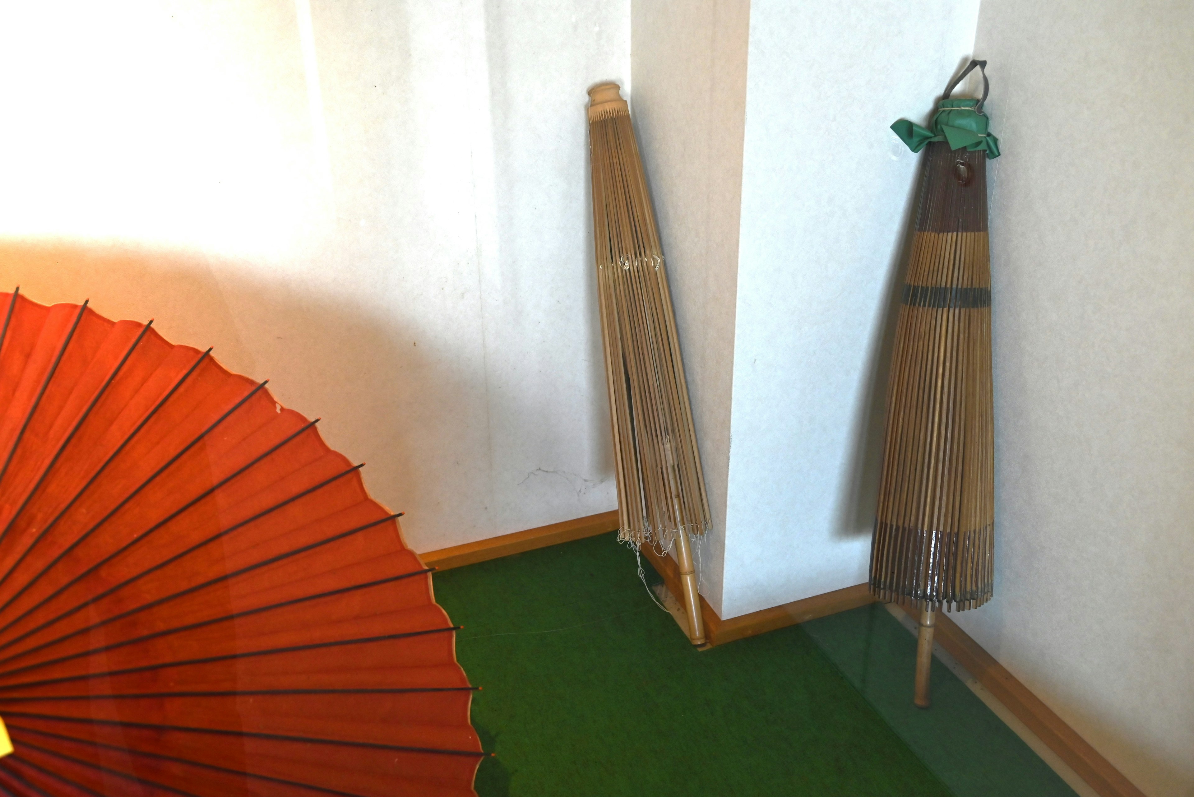 Scène intérieure avec un parapluie traditionnel rouge et des parapluies en bambou adossés au mur