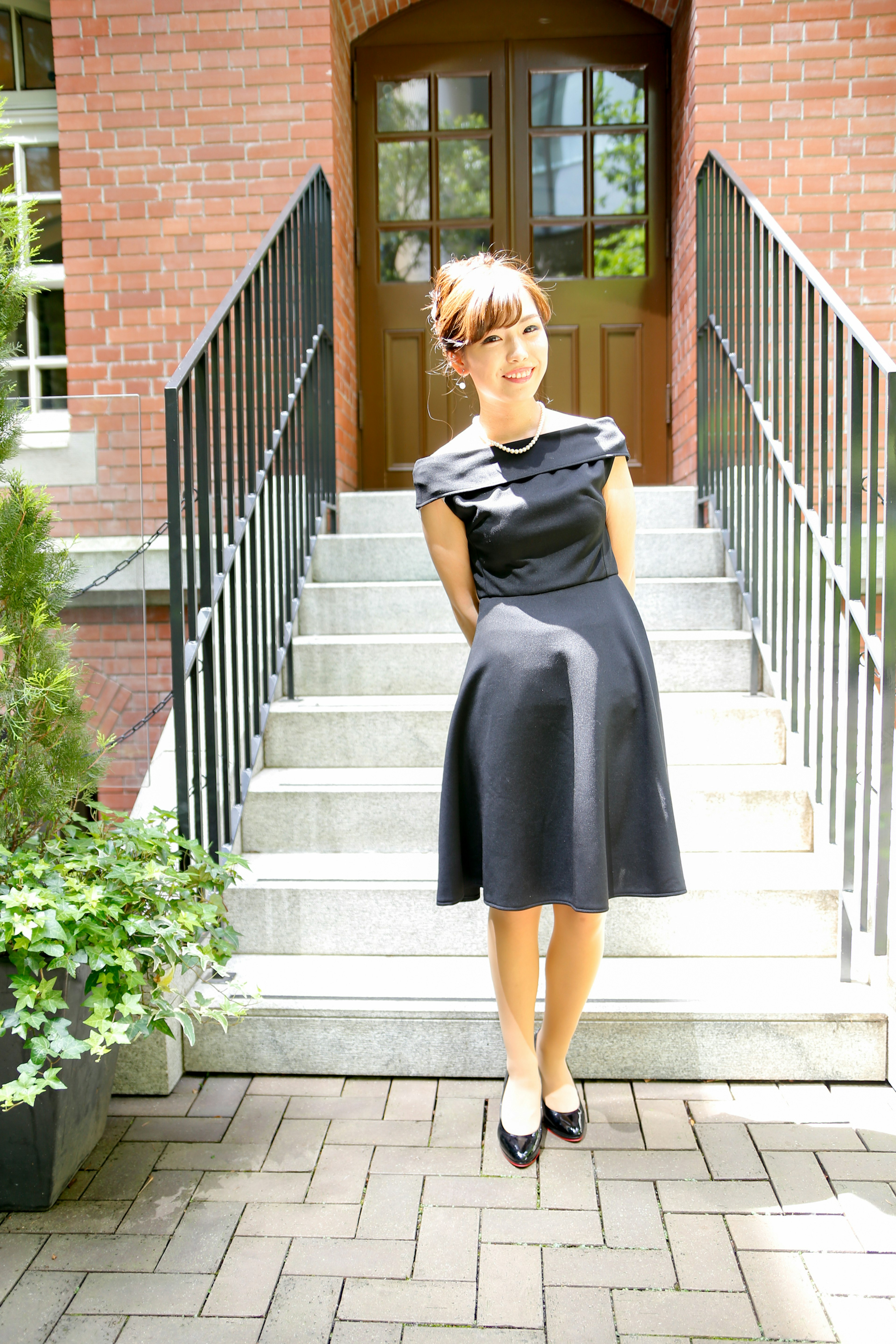 A woman in a black dress posing on a staircase