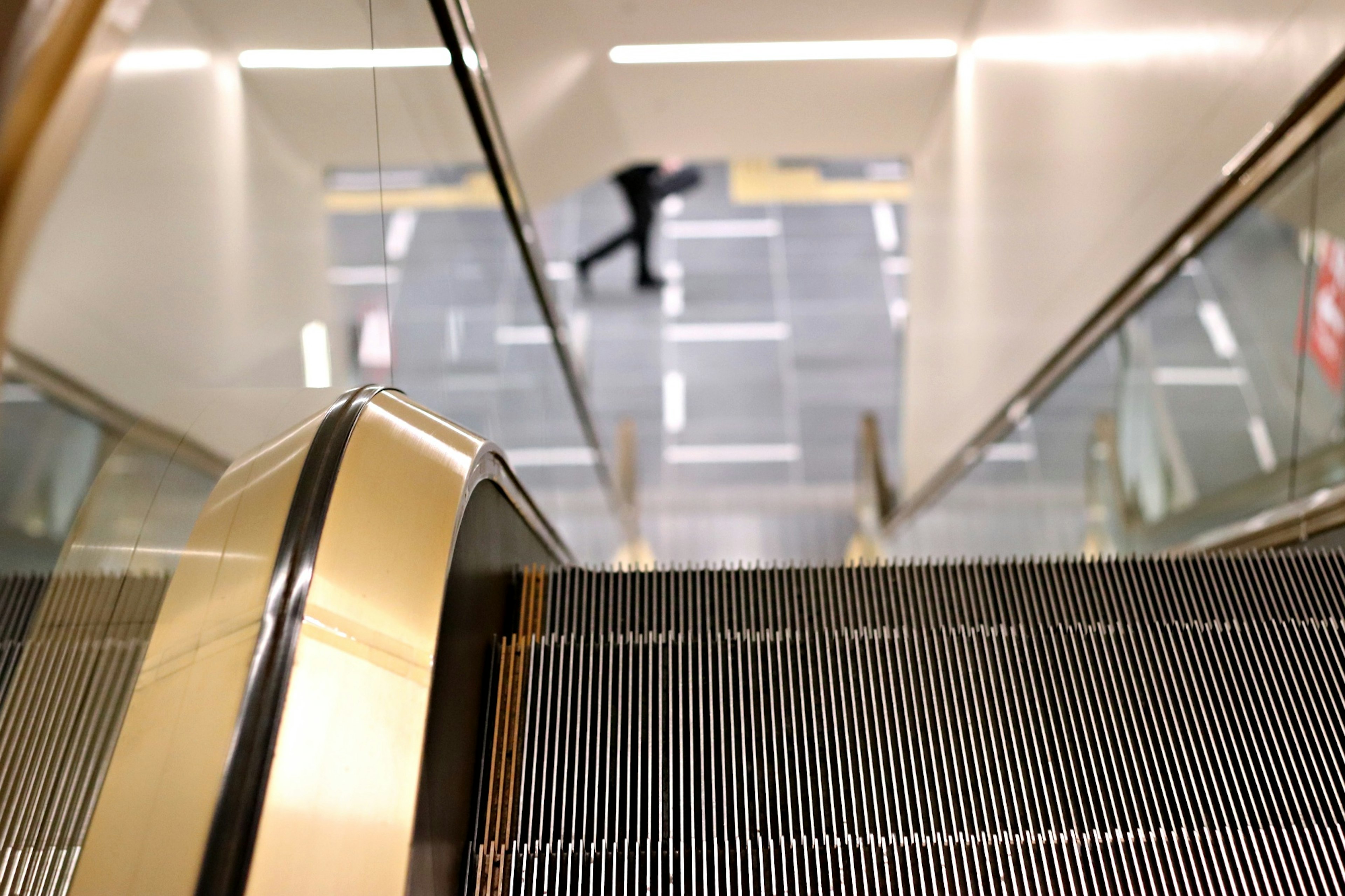 View from above an escalator with a person walking below