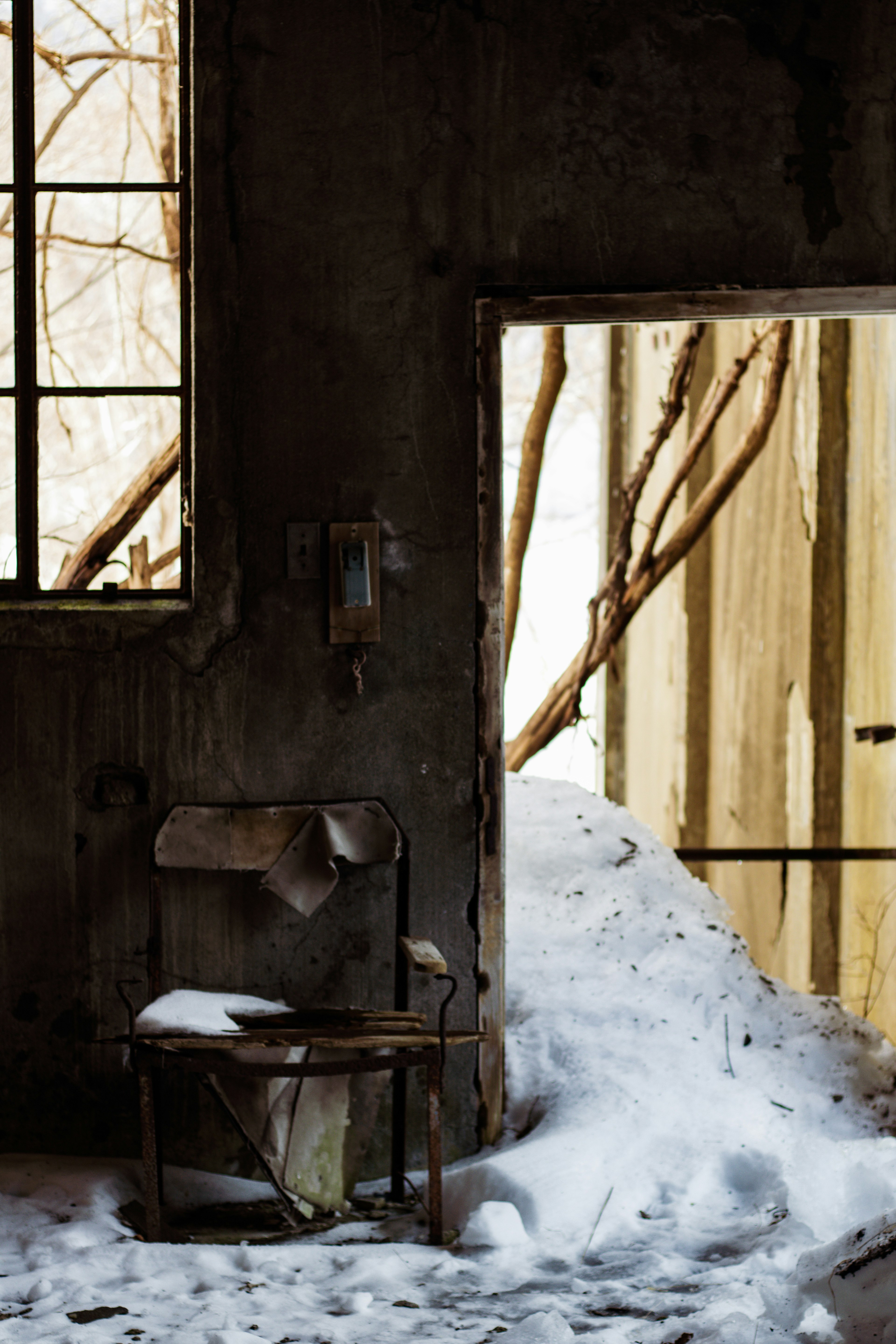 廢棄建築內的舊椅子和被雪覆蓋的地面，門敞開