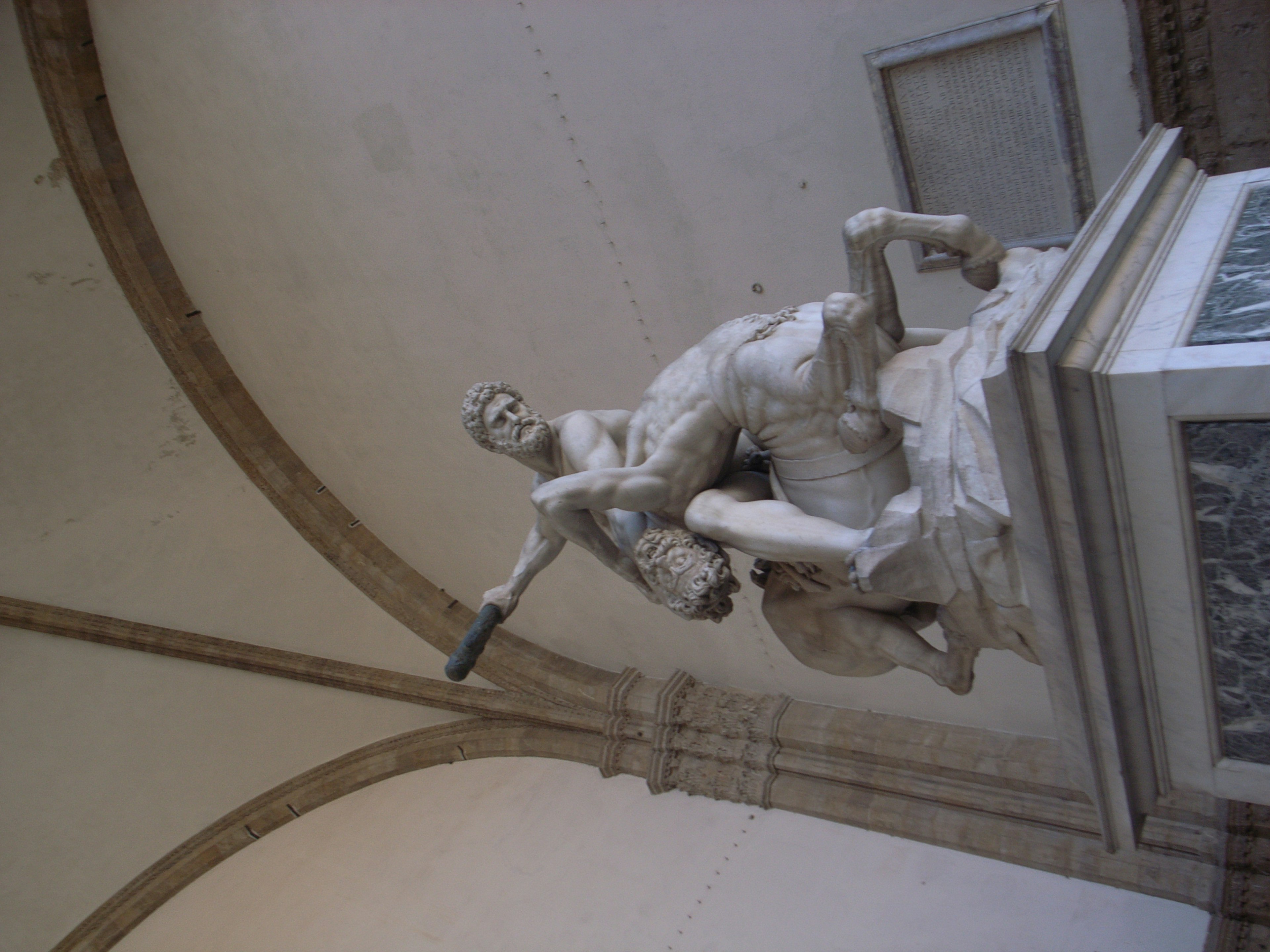 Eine Skulptur eines Mannes, der eine Frau hält, mit einer gewölbten Decke im Hintergrund