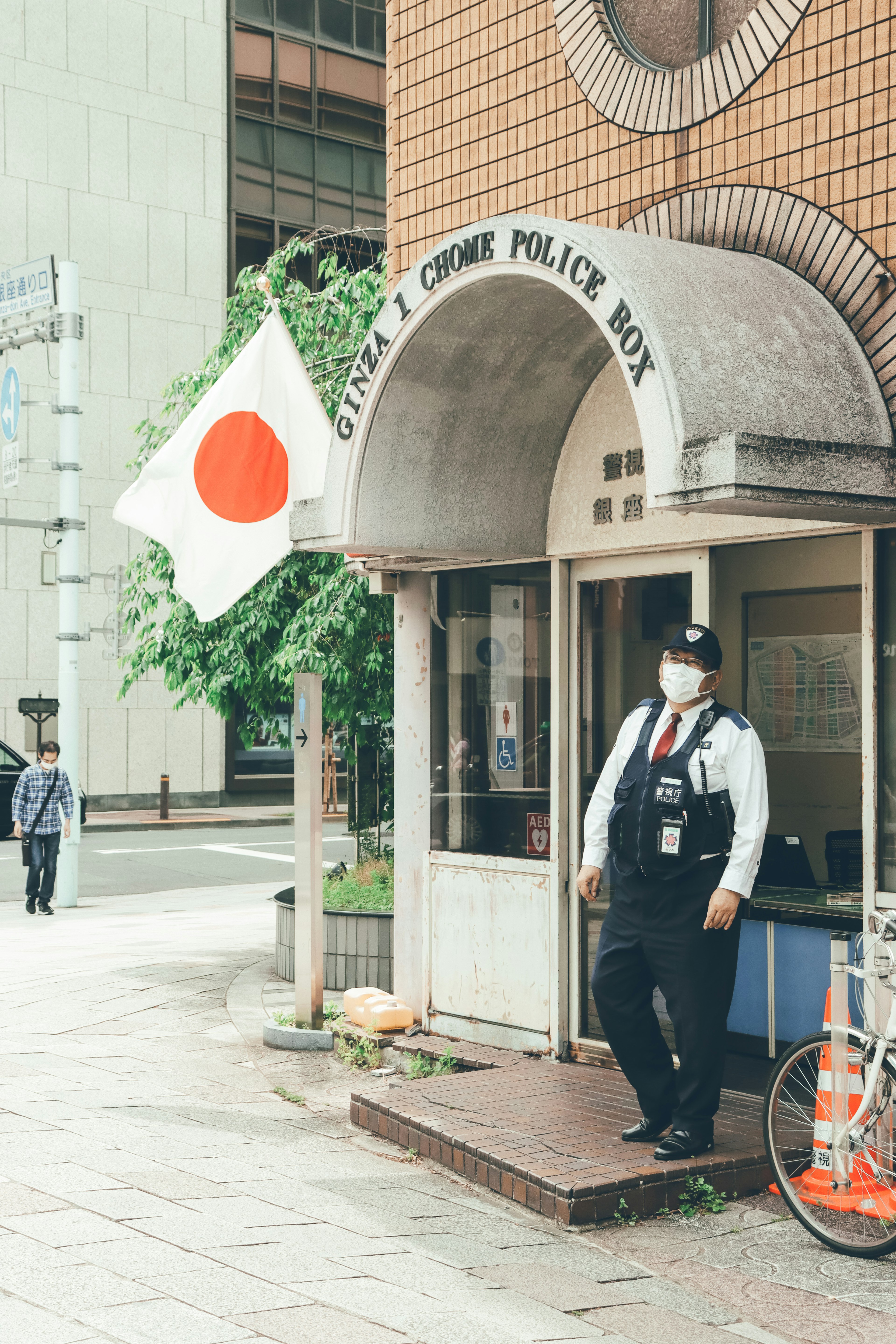 일본 경찰서 앞에 서 있는 경찰관과 일본 국기