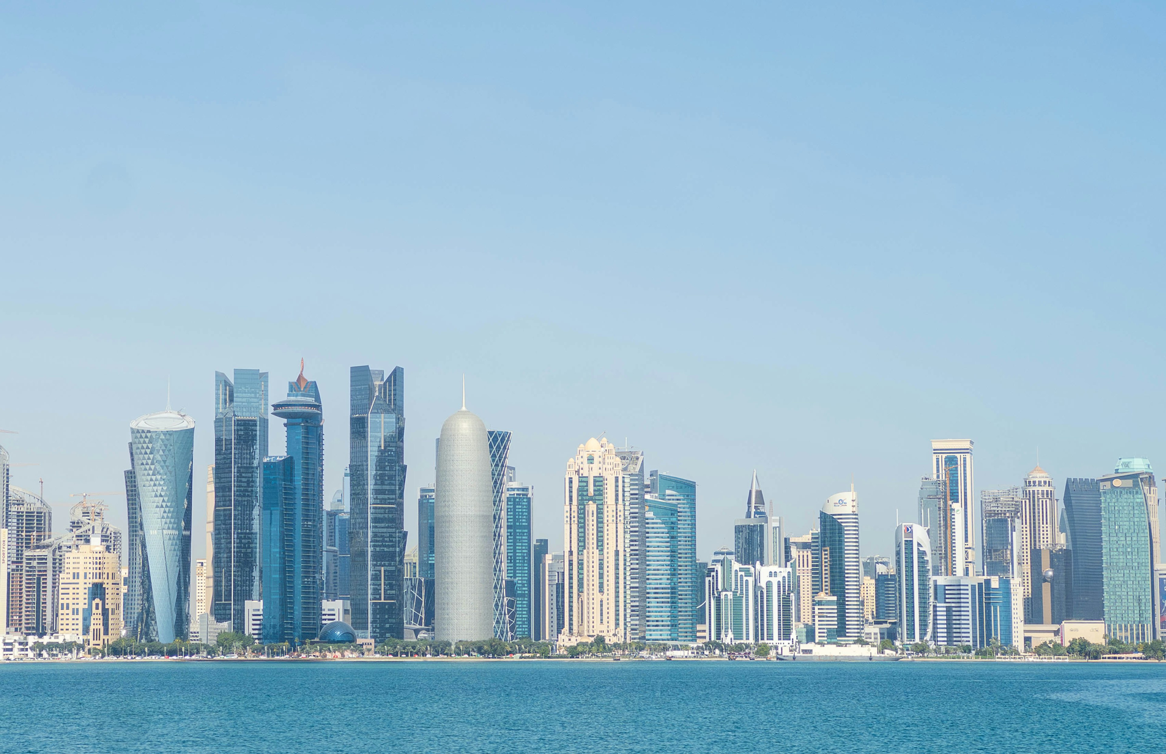 Horizonte de Doha con rascacielos modernos contra un cielo azul claro y el mar