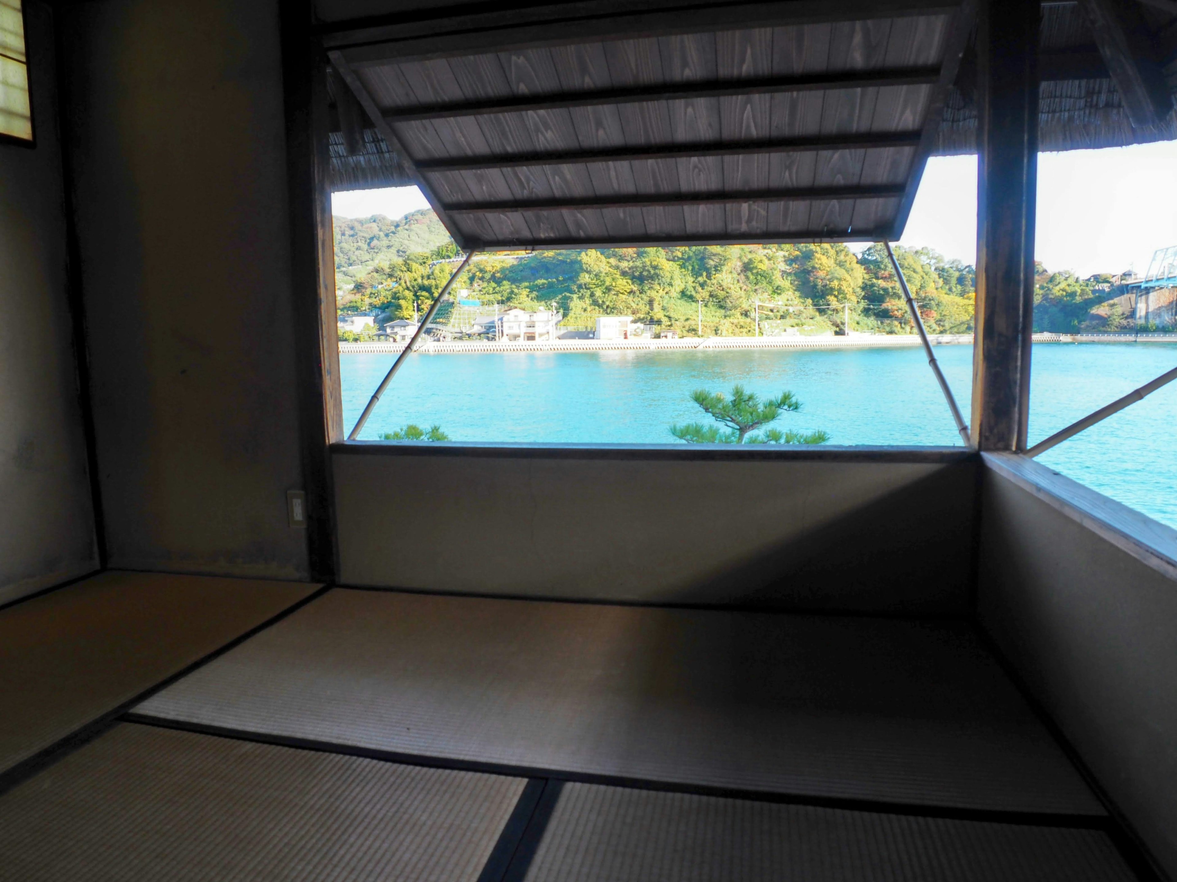 Pemandangan laut tenang dari ruangan Jepang tradisional dengan lantai tatami dan balok kayu